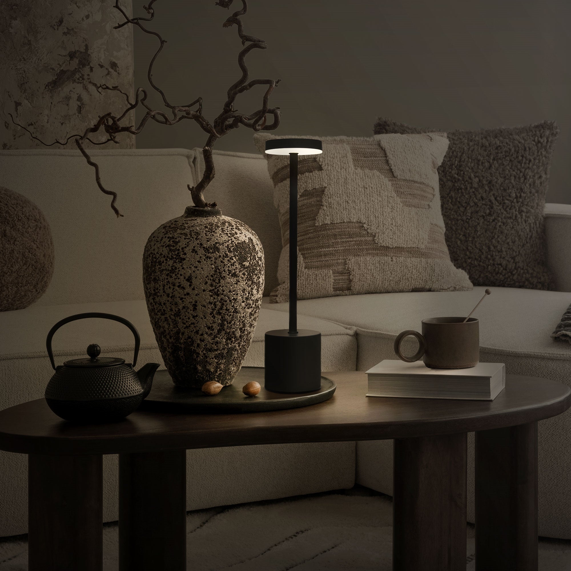 Lampadaire sur une table à côté d'un vase et d'une théière.