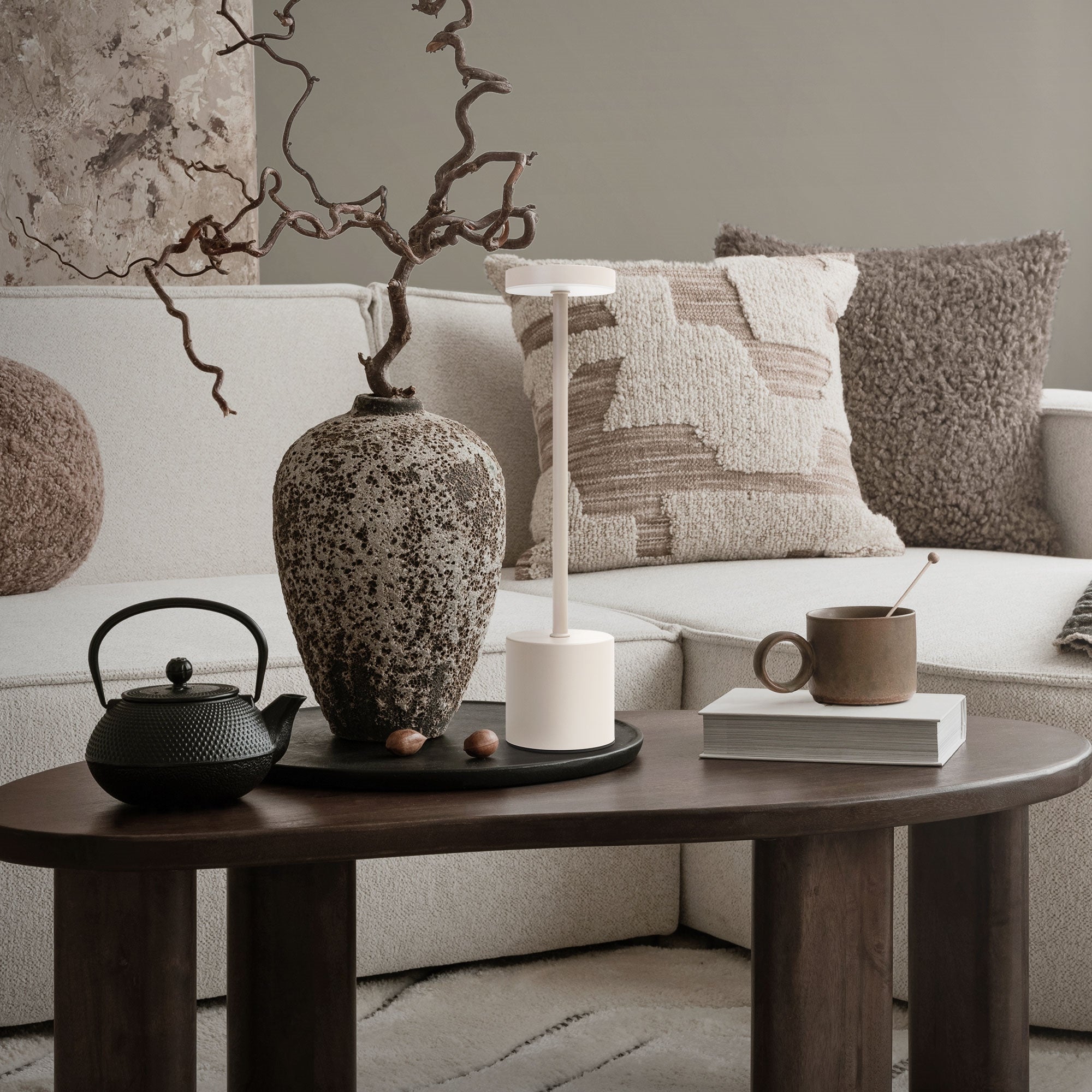 Salon avec lampadaire, vase, théière et tasse sur une table.