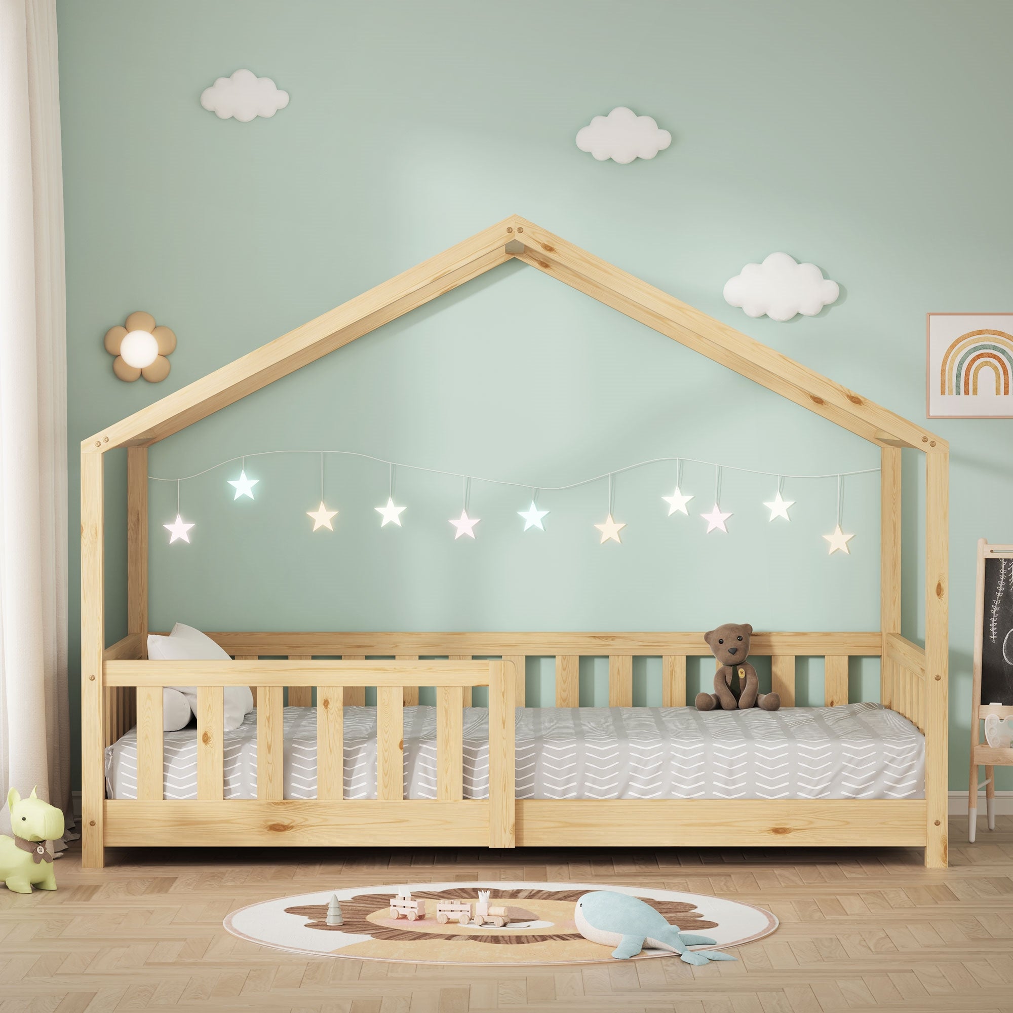 Lit pour enfant de couleur bois en forme de maison avec guirlande lumineuse et jouets.