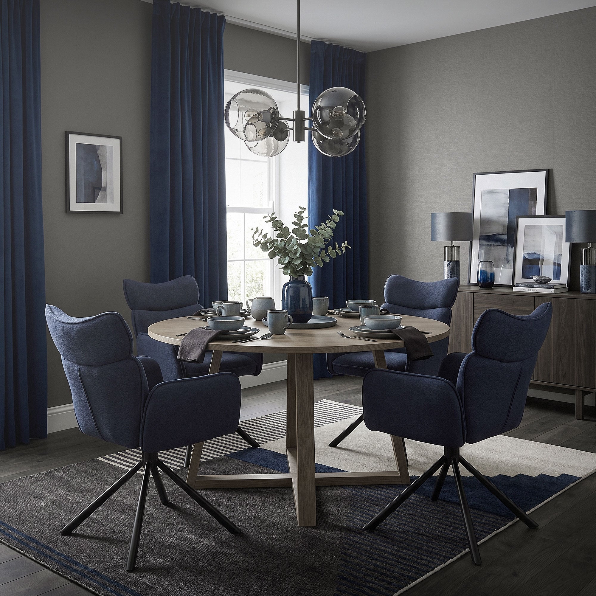 Ein Esszimmer mit einem runden Tisch und blauen Stühlen.