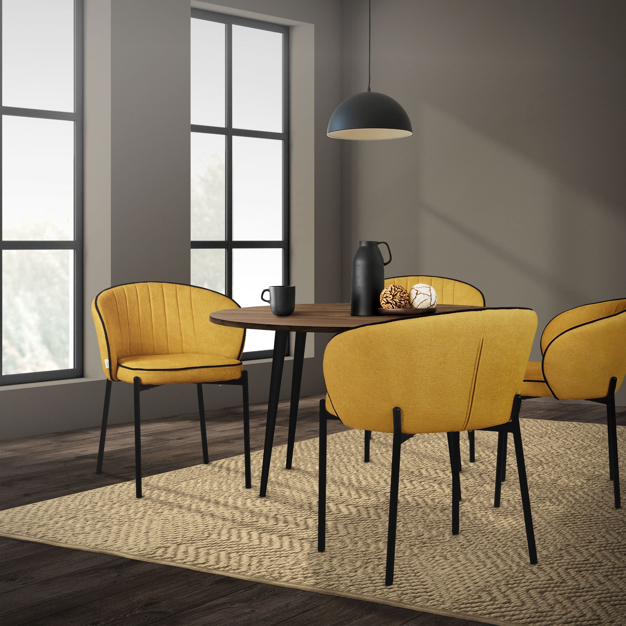 A dining room with a round table and four yellow chairs, illuminated by a pendant light.