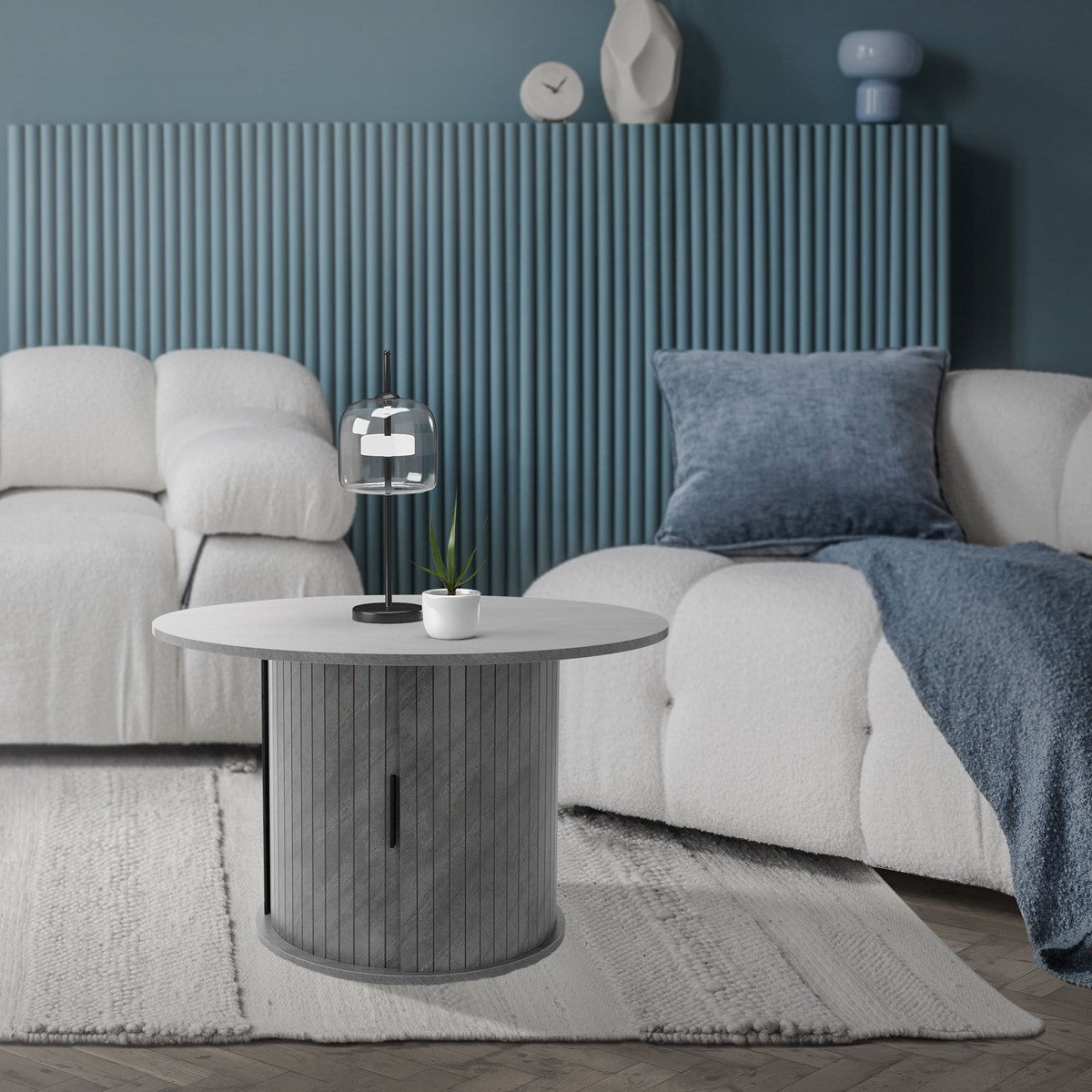 Wohnzimmer mit grauem Tisch, Lampe und beigen Sofas.