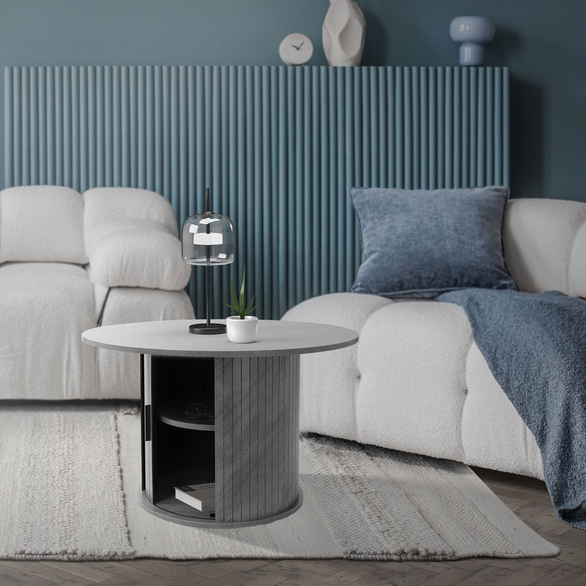 Ein runder Couchtisch mit einer Lampe und einer Pflanze in einem modernen Wohnzimmer.