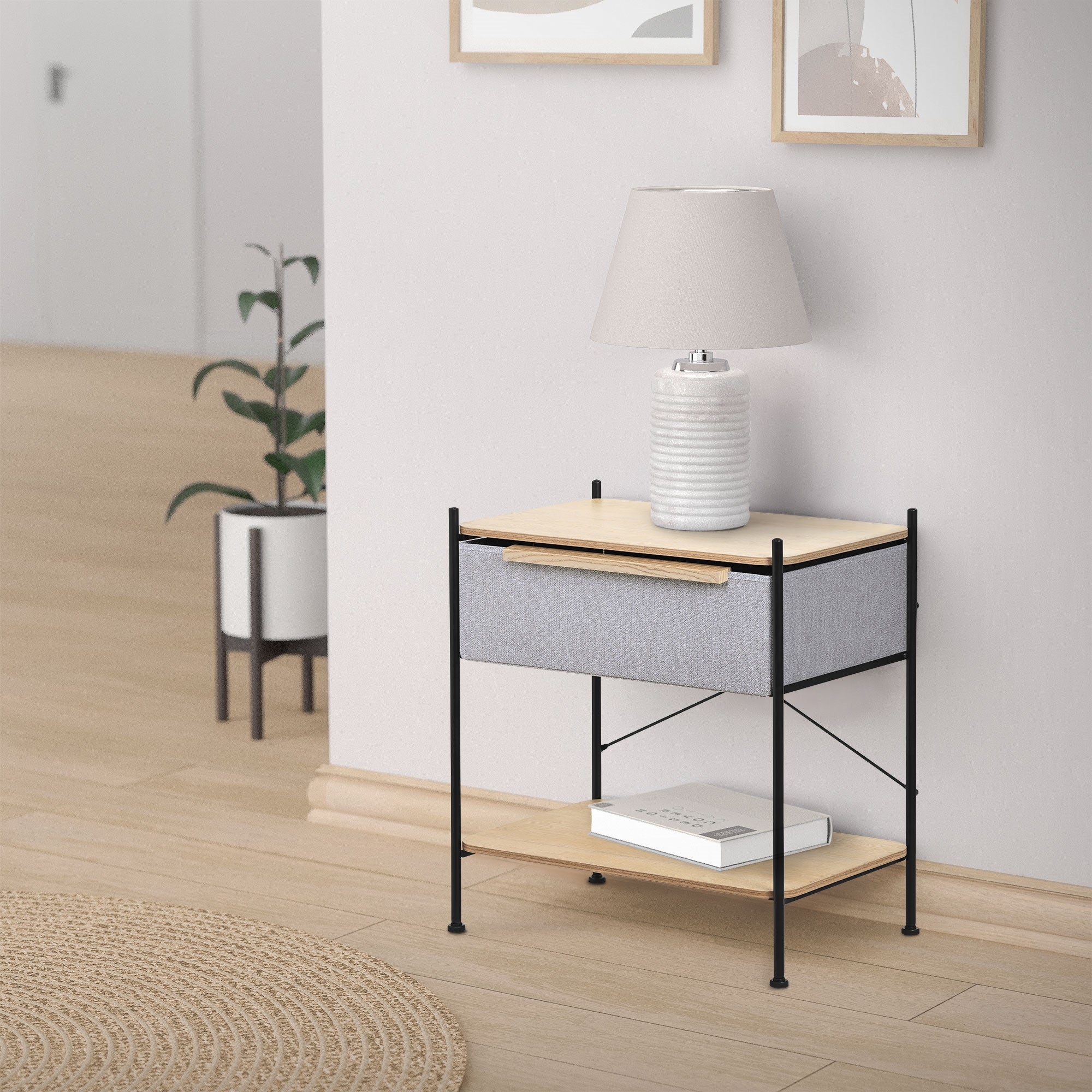 Et natbord med en lampe, en plante og en bog på et trægulv.