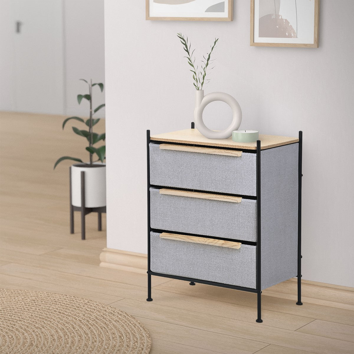 Commode à tiroirs dans une pièce, avec des plantes et des cadres photo en arrière-plan.