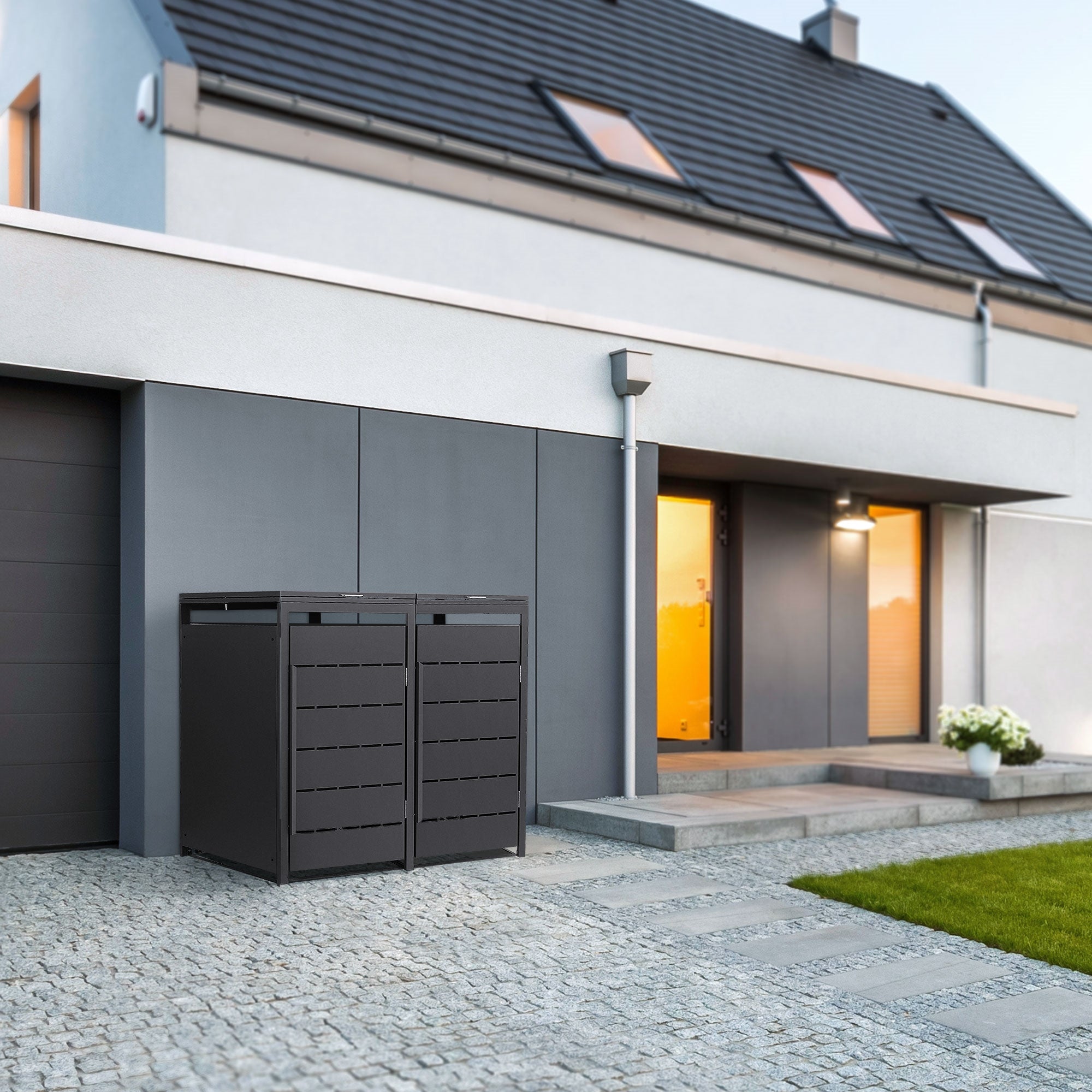 Zwei graue Mülltonnenboxen vor einem modernen Haus mit Garten.