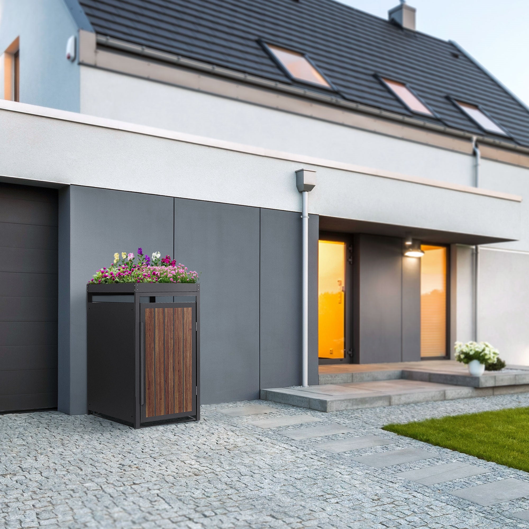 Moderne Mülltonnenbox mit Holzverkleidung und Blumen auf dem Deckel vor einem Haus.
