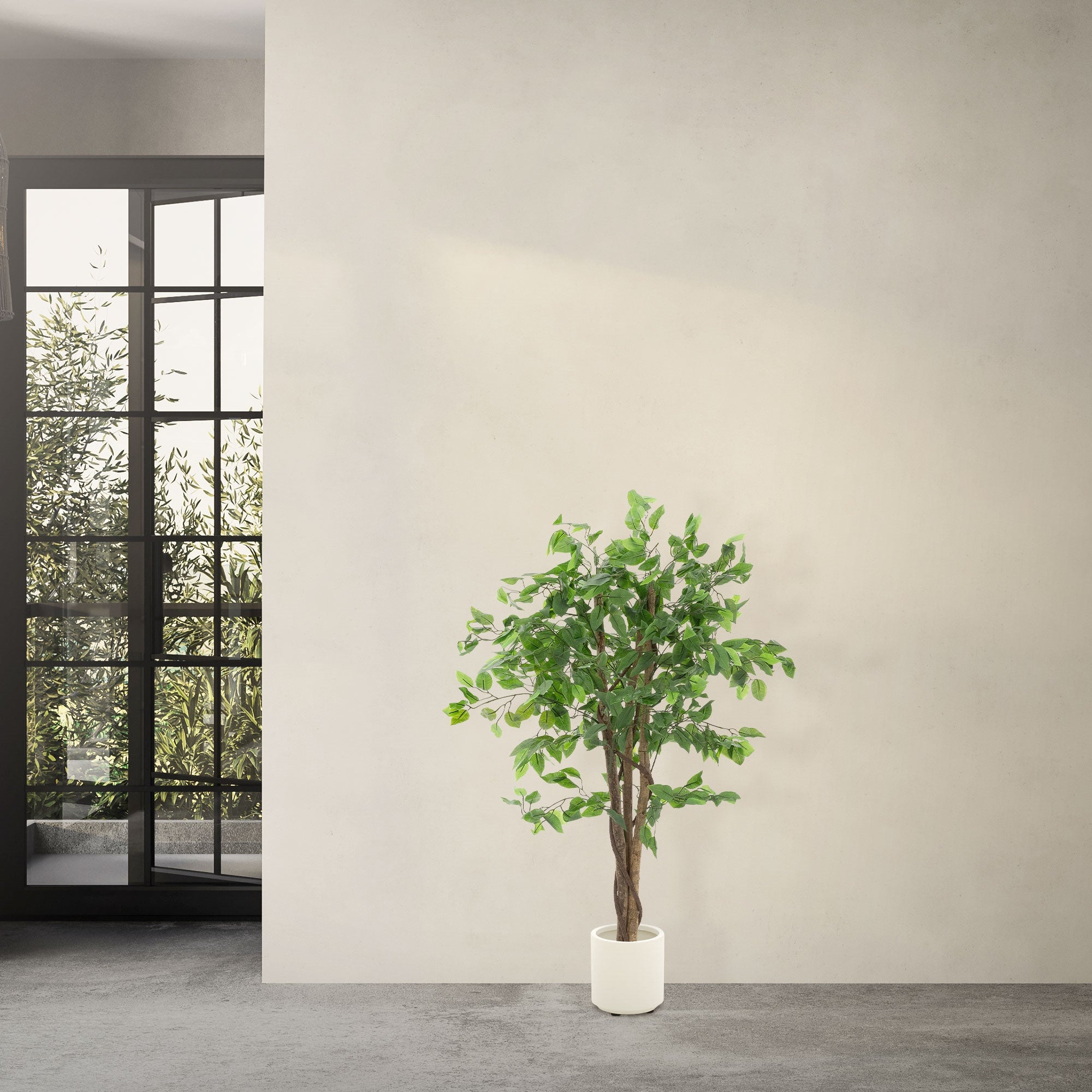 An artificial tree in a white pot in front of a window with a view outside.