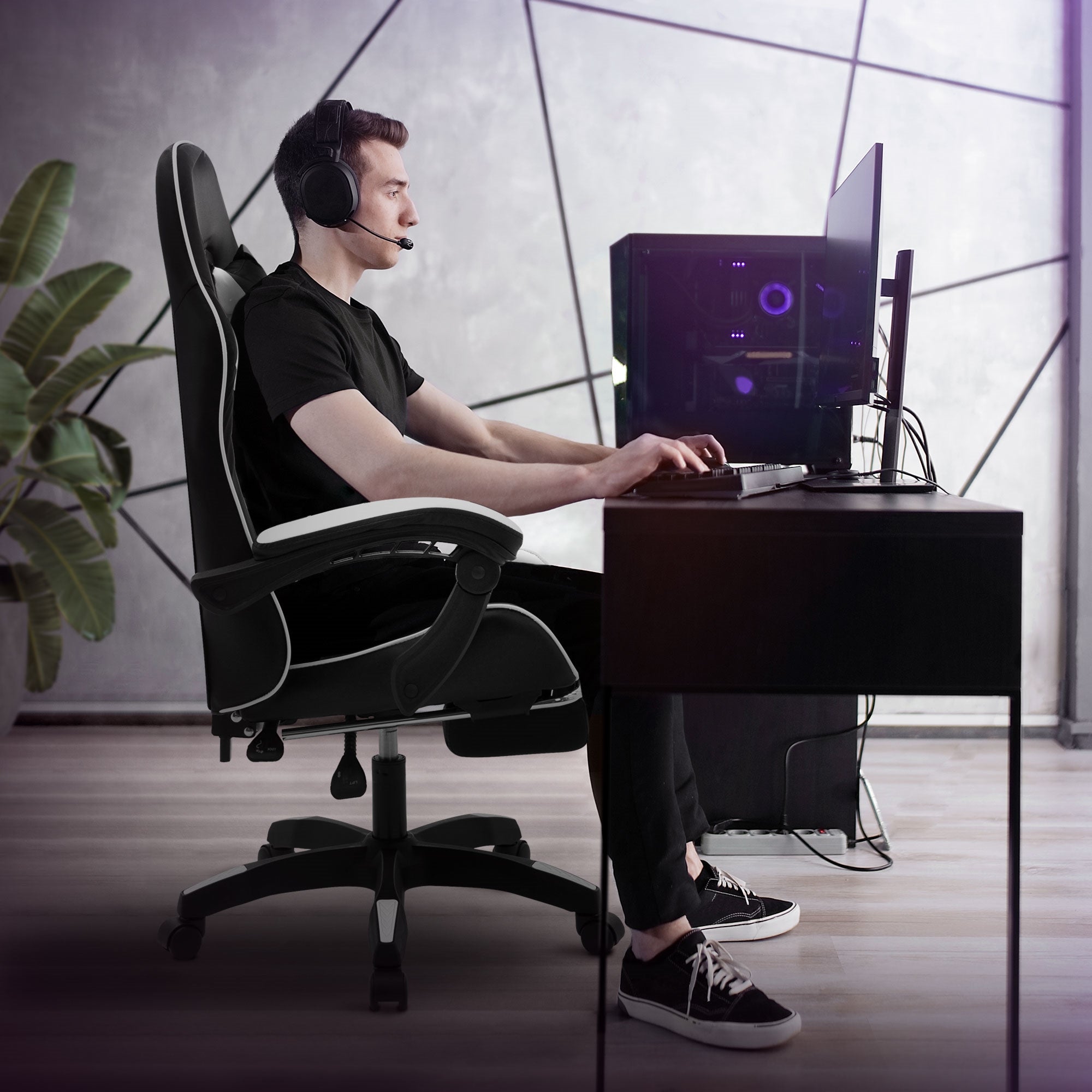 Person sidder ved et skrivebord i en gamingstol med headset og computer.