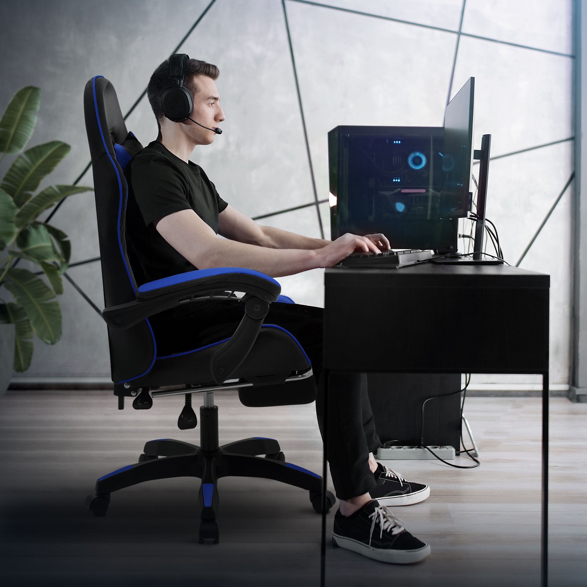 Fiatal férfi ül egy íróasztalnál gamer PC-vel és fejhallgatóval.