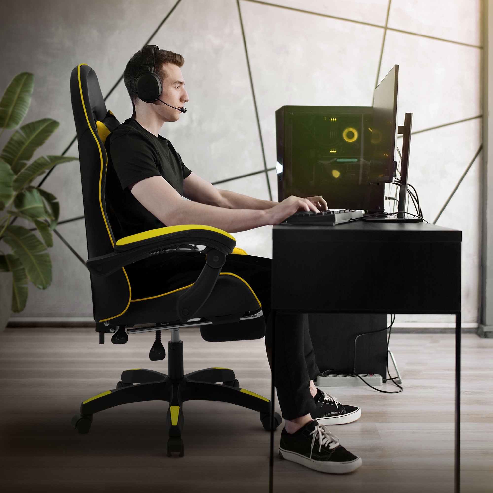 Mann sitzt an Schreibtisch in Gaming-Stuhl mit Headset.