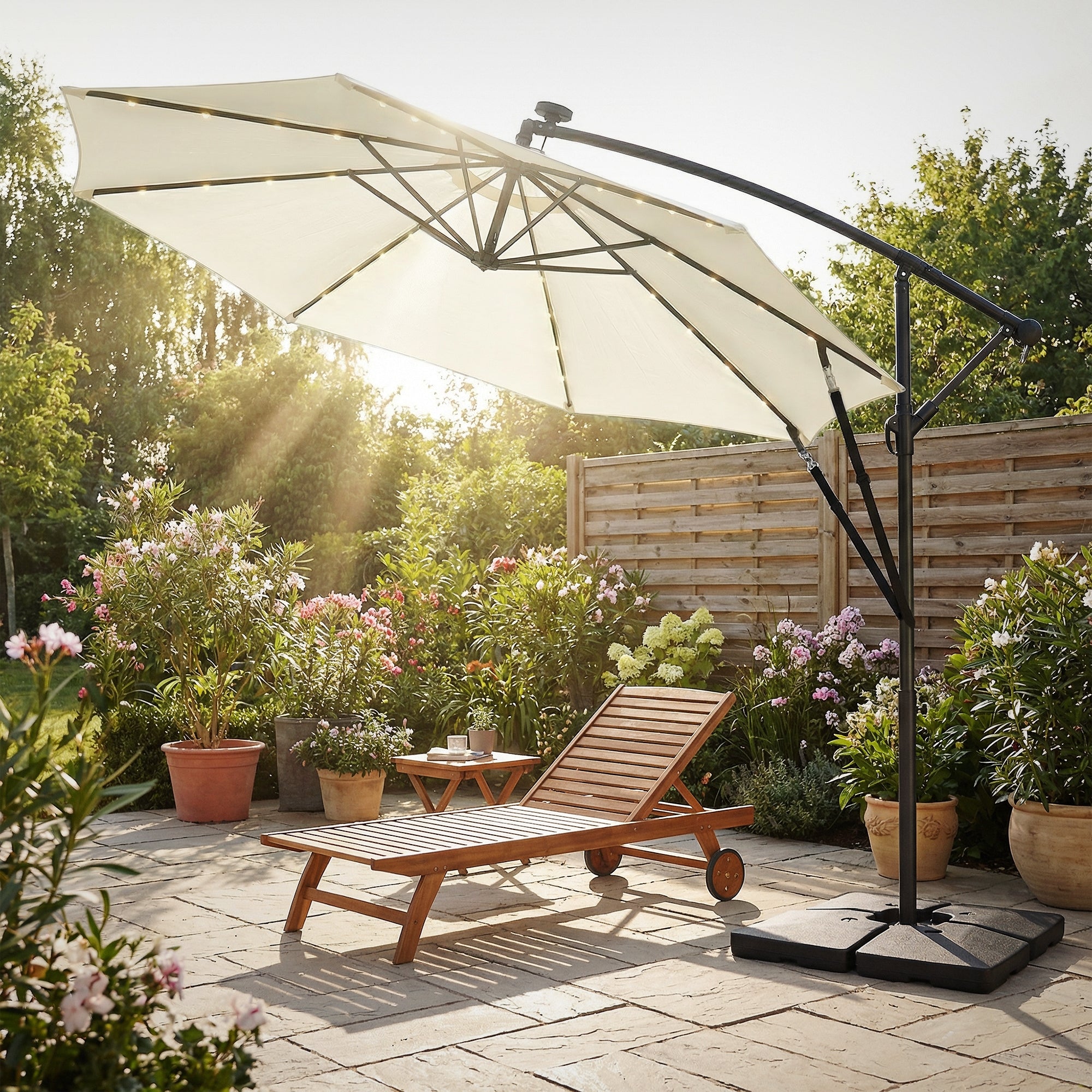 Sonnenschirm über einer Liege in einem Garten mit Blumen und einer Holzterrasse.