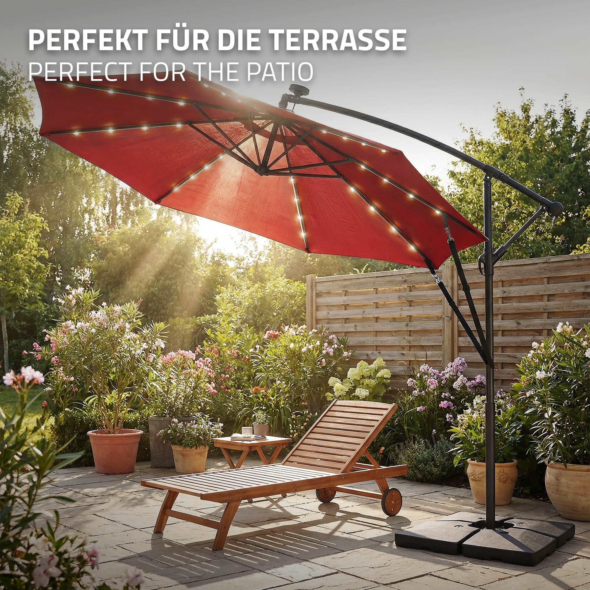 Roter Sonnenschirm mit Lichterkette, neben einer Liege auf einer Terrasse.