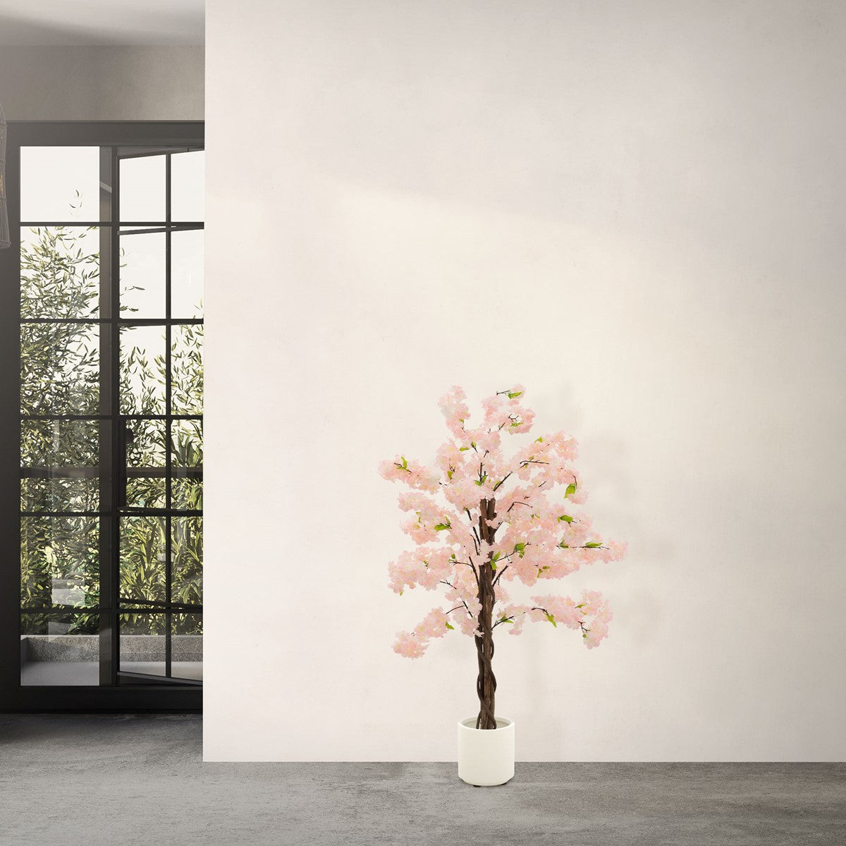 Albero artificiale con fiori rosa davanti a una parete e grandi finestre.