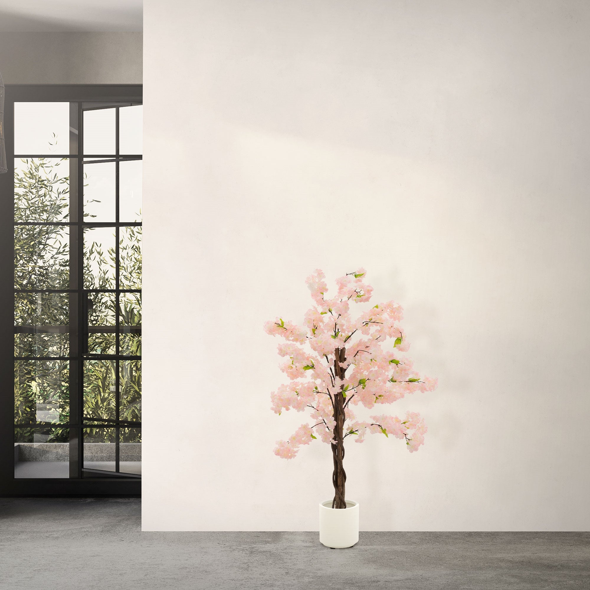 Albero artificiale con fiori rosa davanti a una parete e grandi finestre.