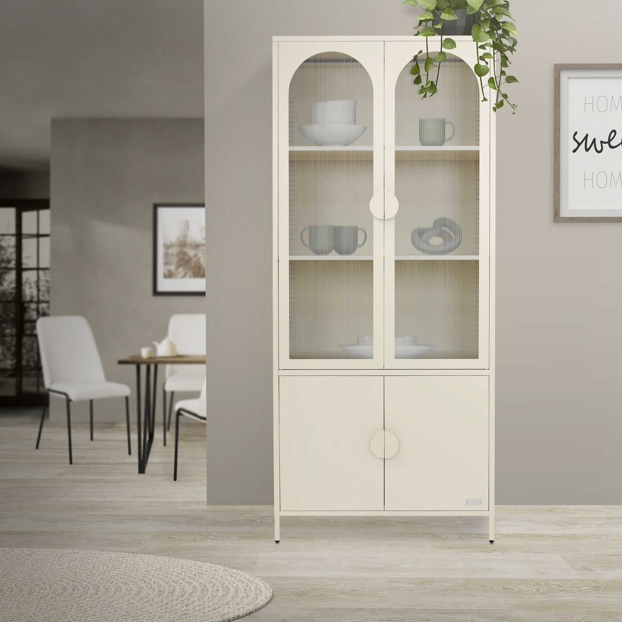 Ein heller Schrank mit Glastüren, Pflanzen und einem Tisch im Hintergrund.