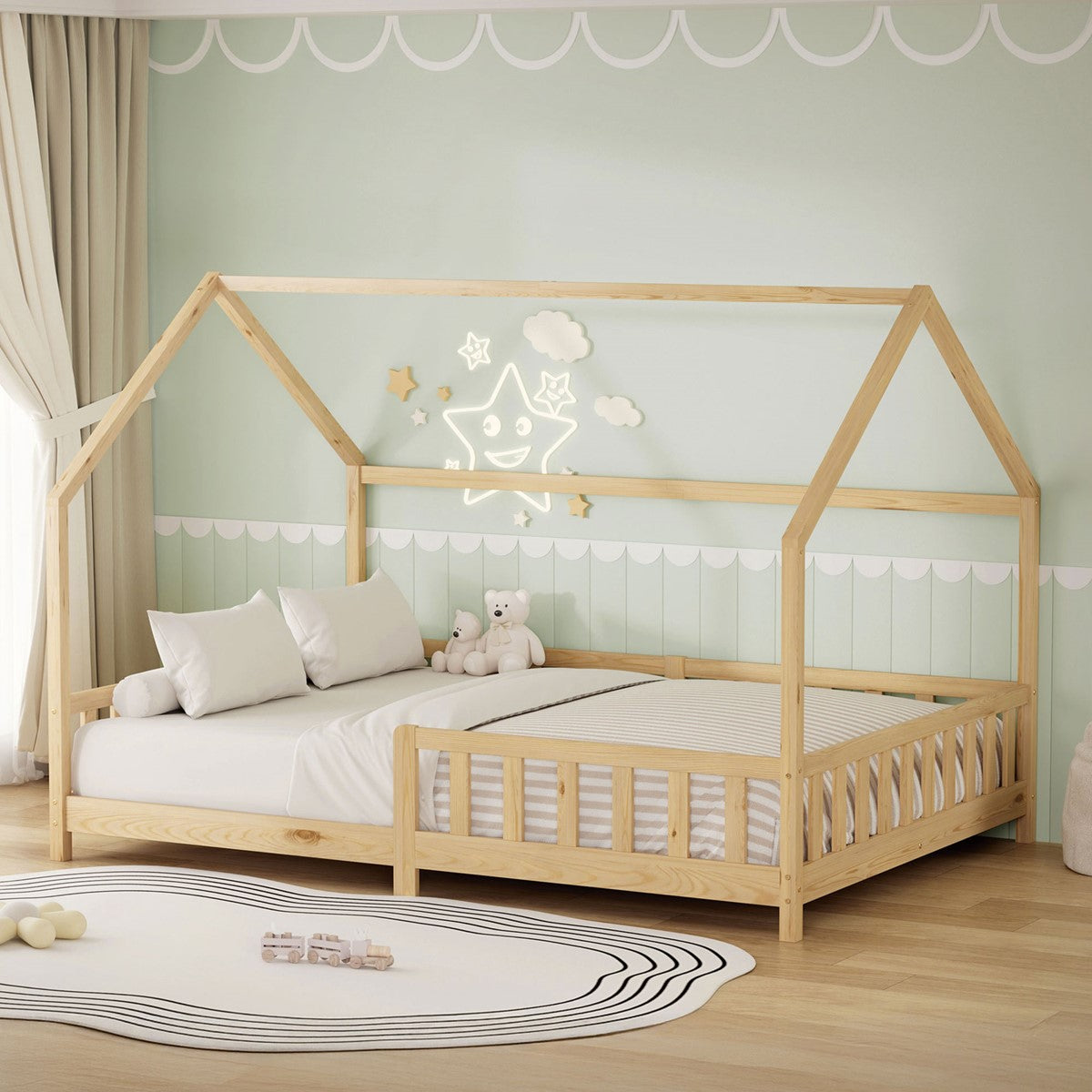 A wooden house-shaped children's bed with pillows and a stuffed animal on a matte surface.