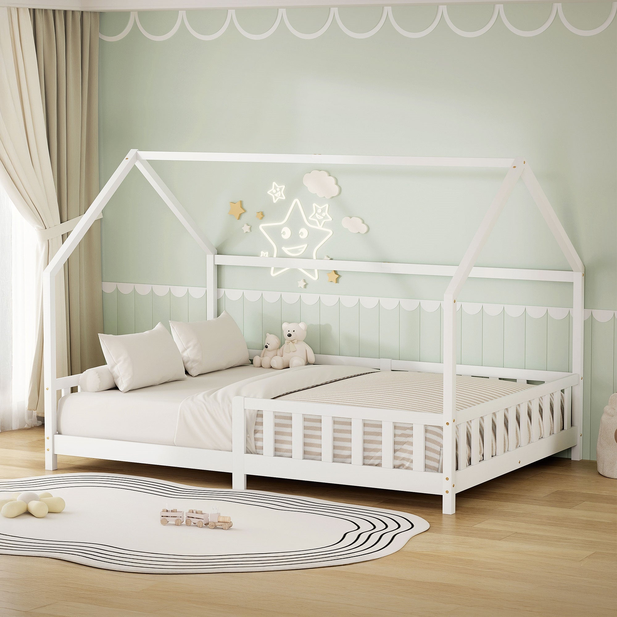 Ein Kinderbett in Hausform mit Kissen und einem Plüschtier auf einer matten Oberfläche.