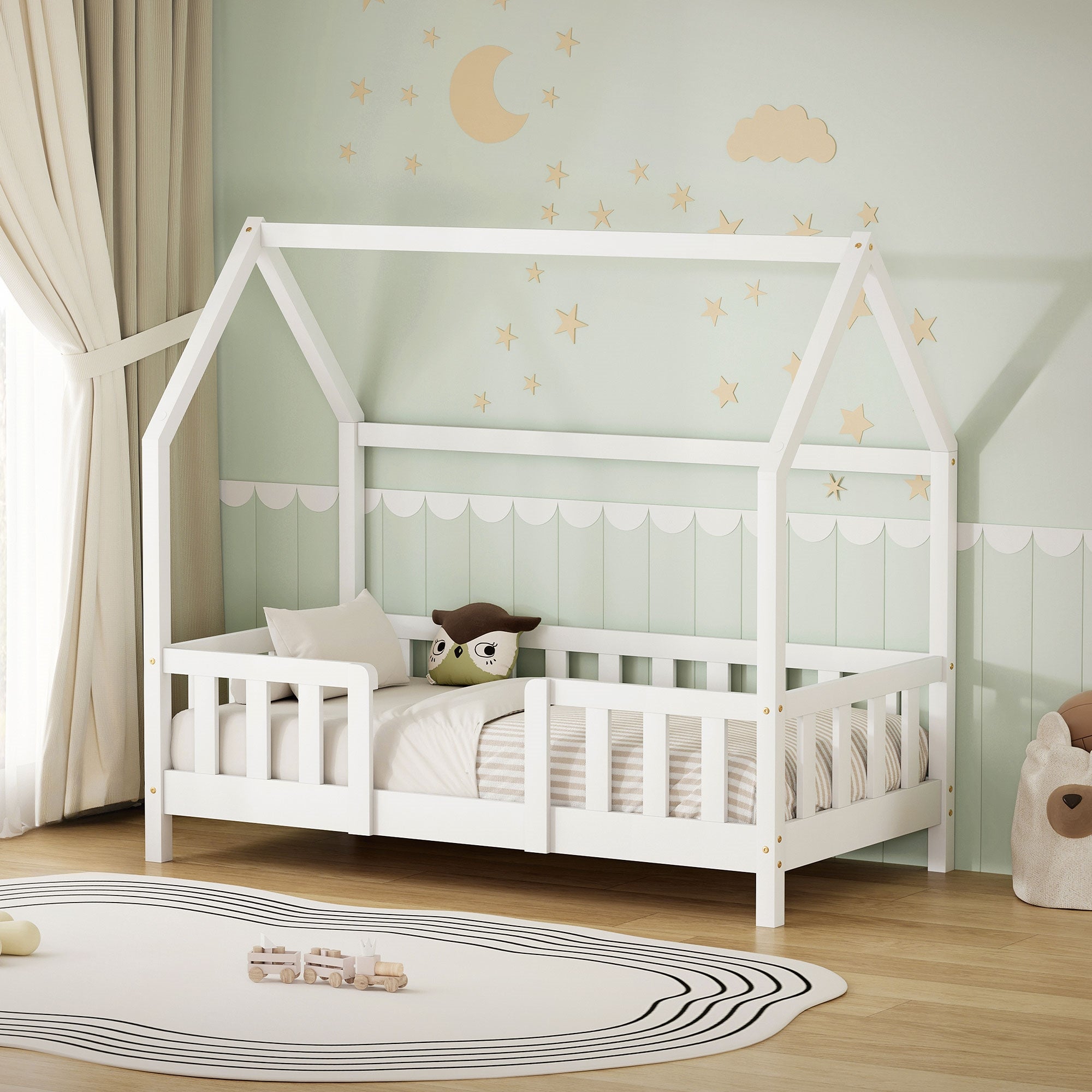 Weißes Kinderbett mit Kissen und Decke in einem hellen Raum.
