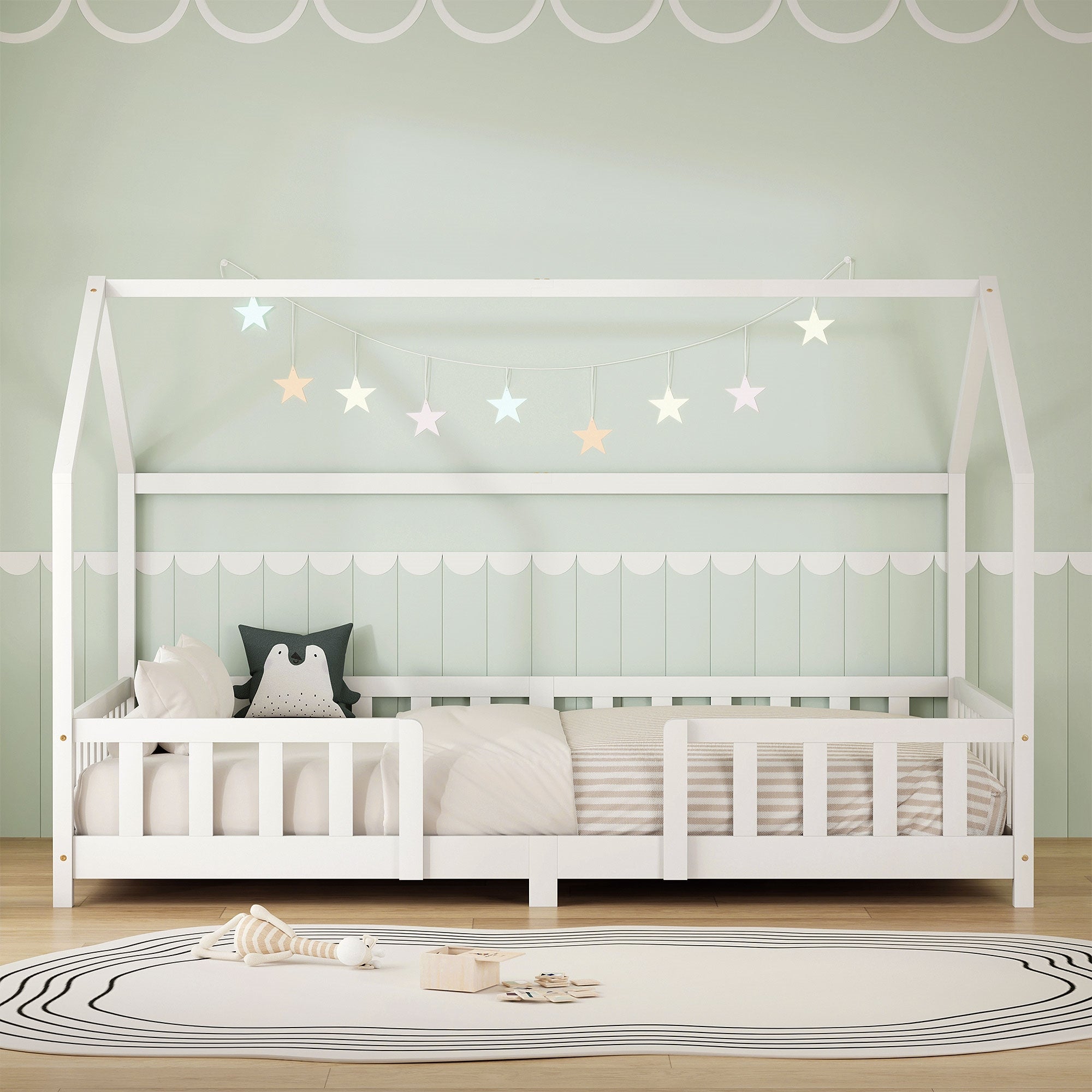 Cama infantil blanca en diseño de casa, con almohadas y luces de estrellas, sobre fondo verde.