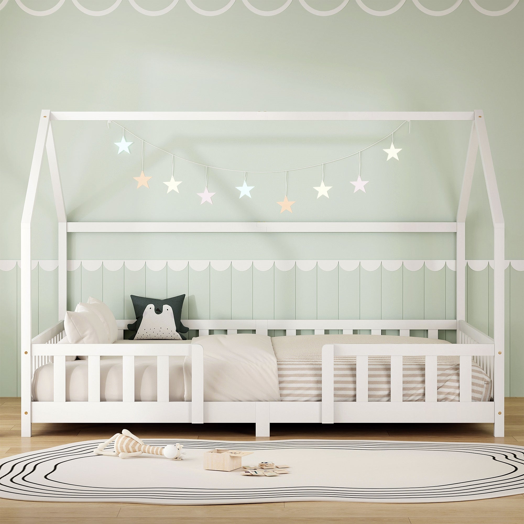 Weißes Kinderbett mit Kissen und Sternenlichtern in einem hellen Raum.
