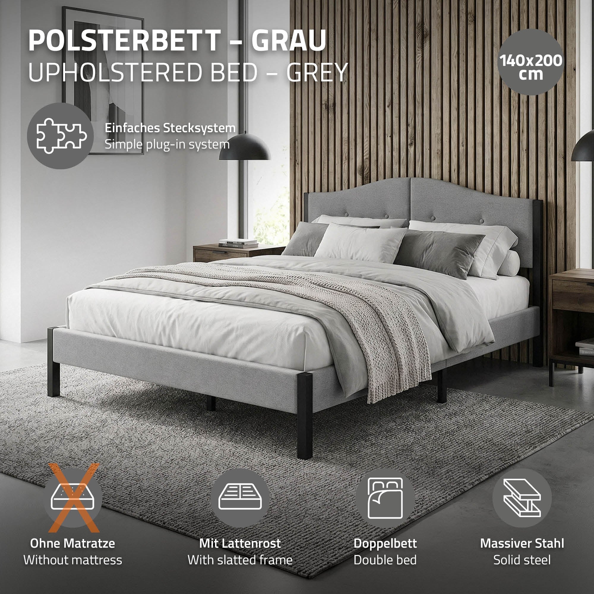 Ein graues Polsterbett mit einer Decke und Kissen auf einem Teppich.