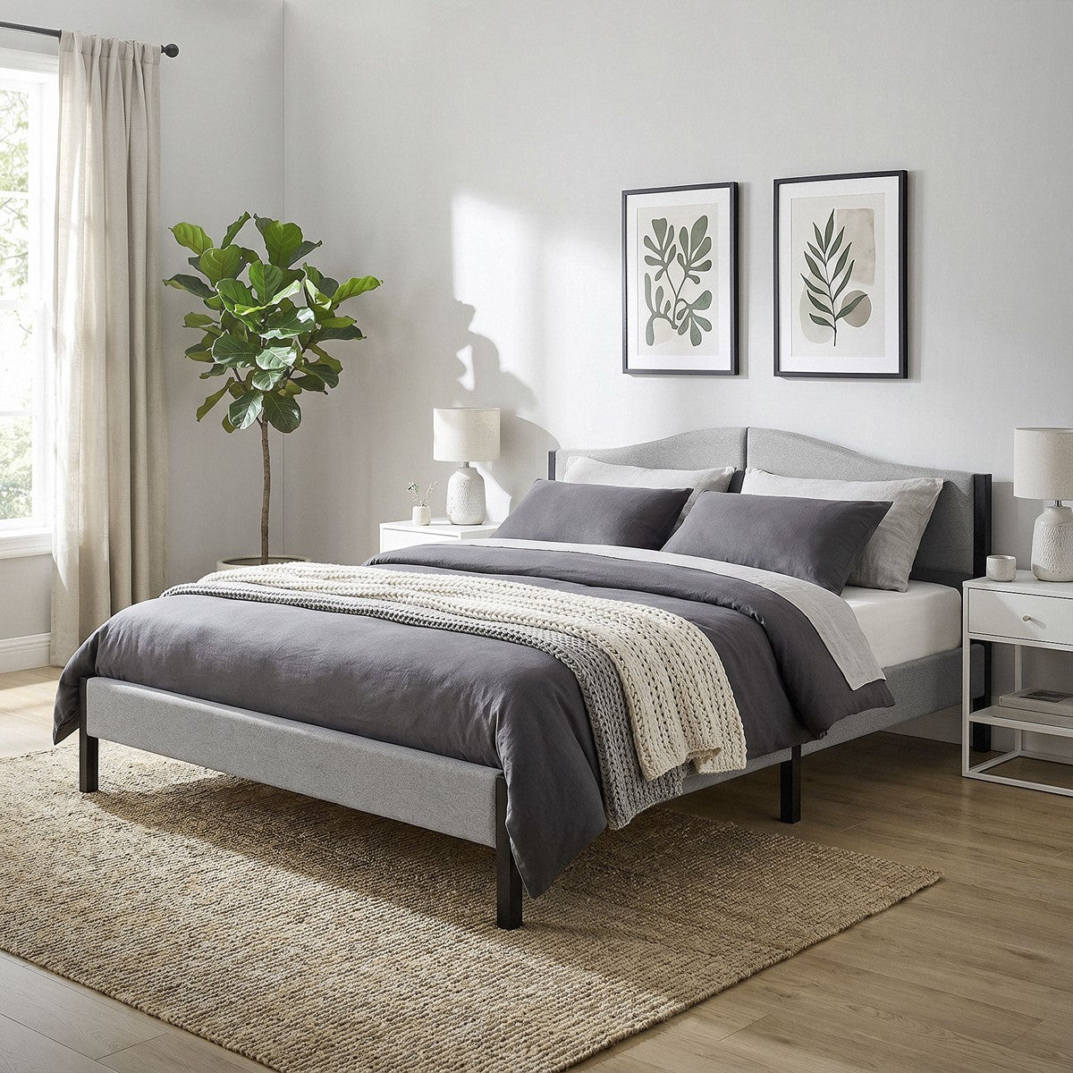 A bedroom with a gray bed, plants, and pictures on the wall.