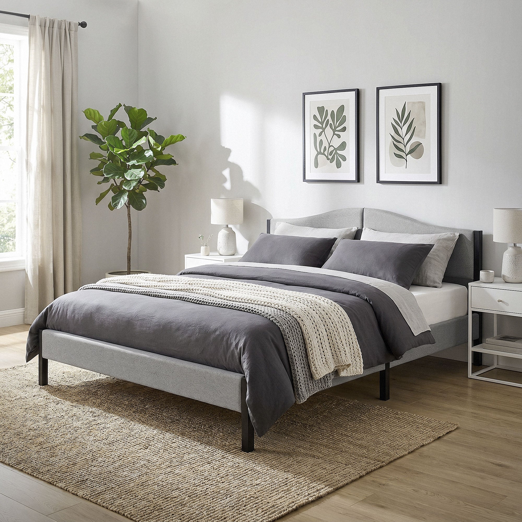 Ein Schlafzimmer mit einem grauen Bett, Pflanzen und Bildern an der Wand.