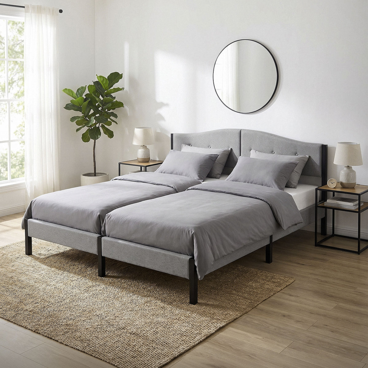 Two single beds with gray bedding and a round wall mirror.