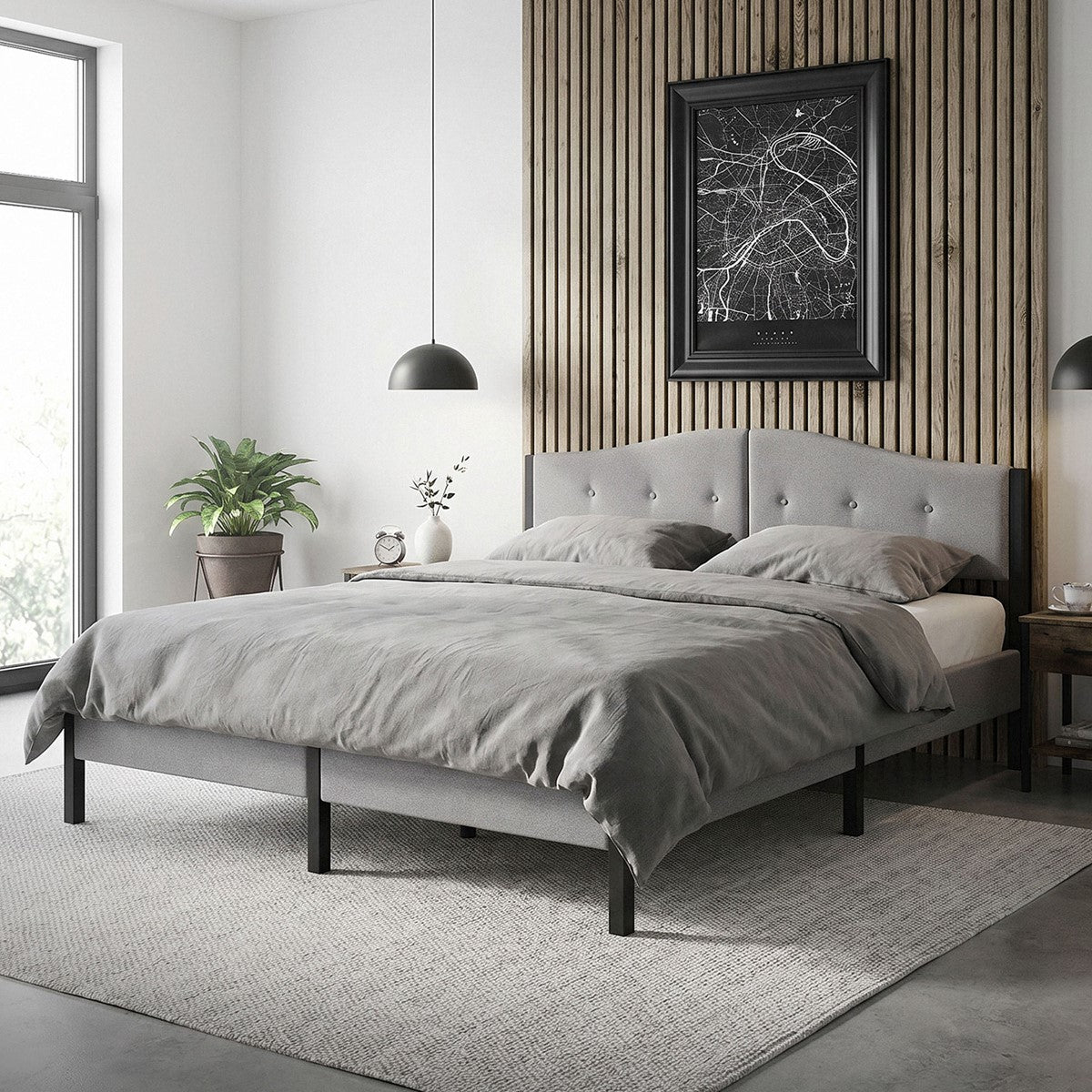 Une chambre avec un lit gris, des plantes et une œuvre d’art au mur.