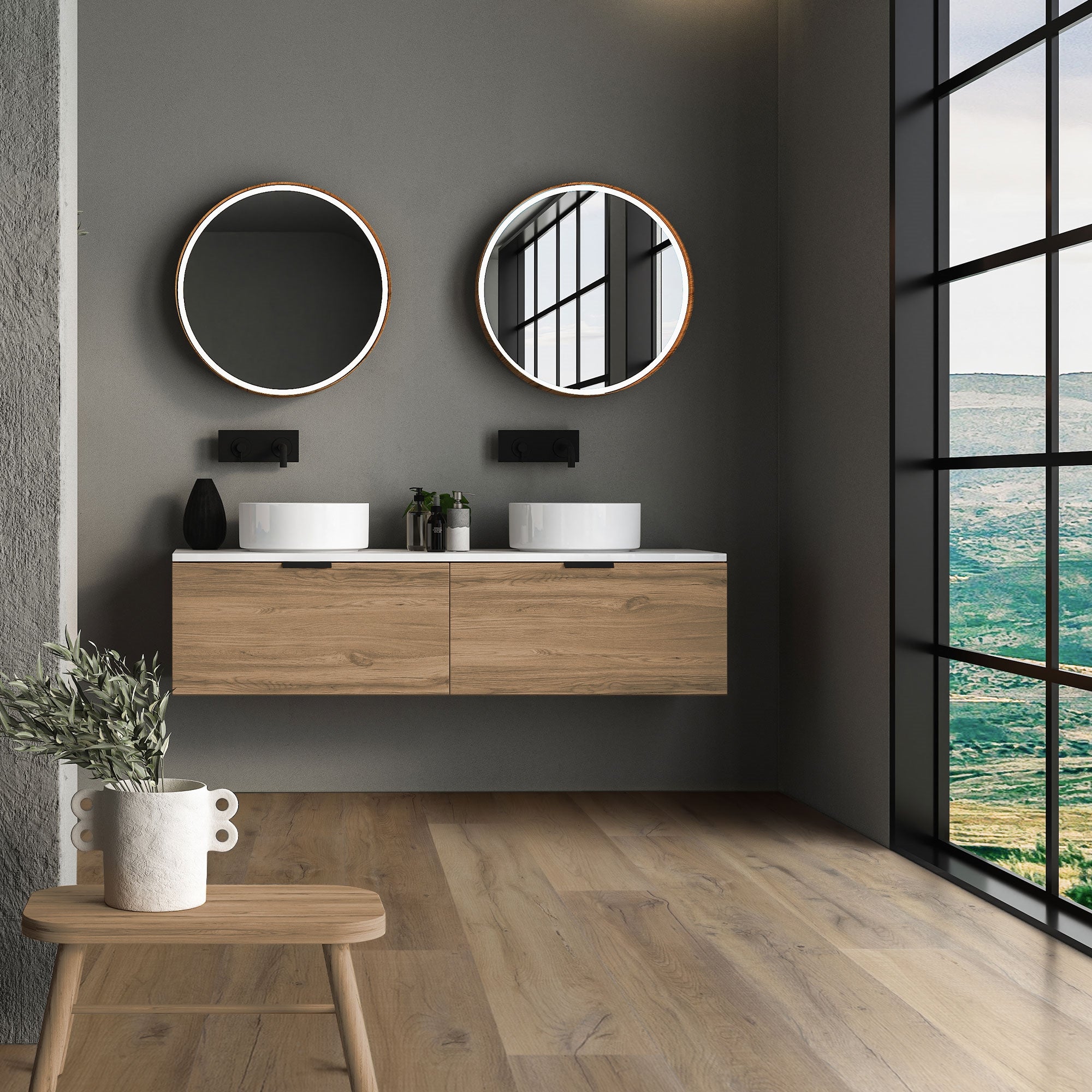 Baño moderno con dos espejos redondos y lavabo de madera frente a grandes ventanas.