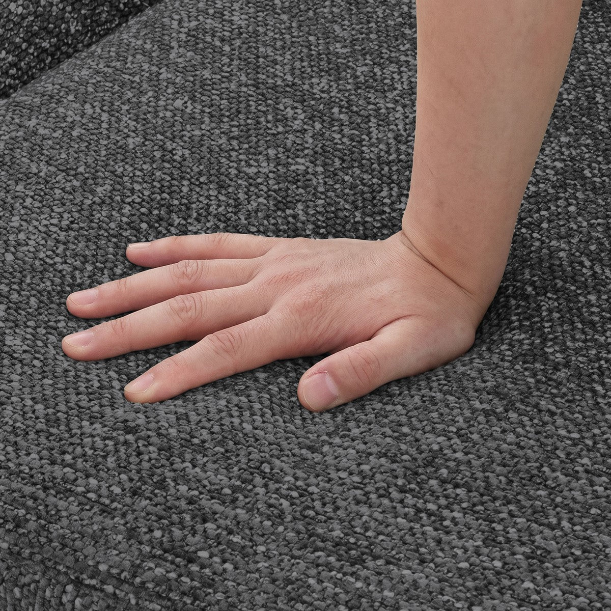 Eine Hand drückt auf den dunkelgrauen, grob gewebten Sitzbezug.