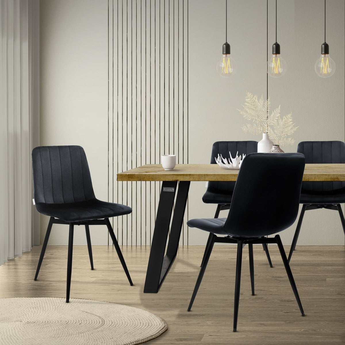 Zwarte gestoffeerde stoelen staan rond een houten tafel in een lichte eetkamer met hanglampen.