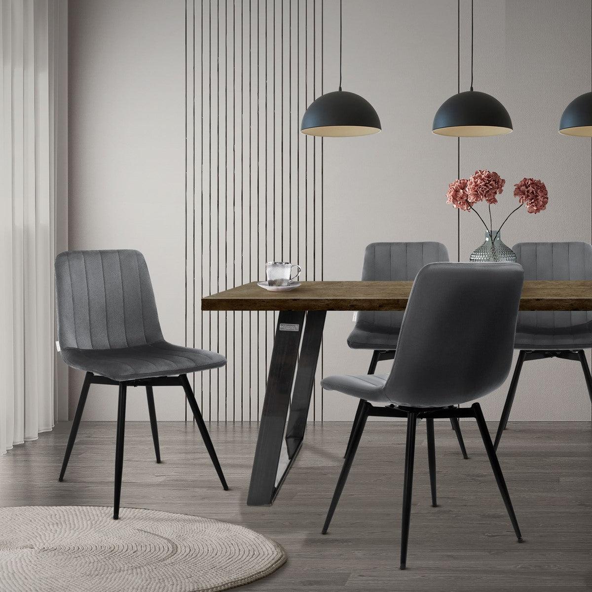 Grijze stoelen staan aan een houten eettafel in een lichte kamer met hanglampen.