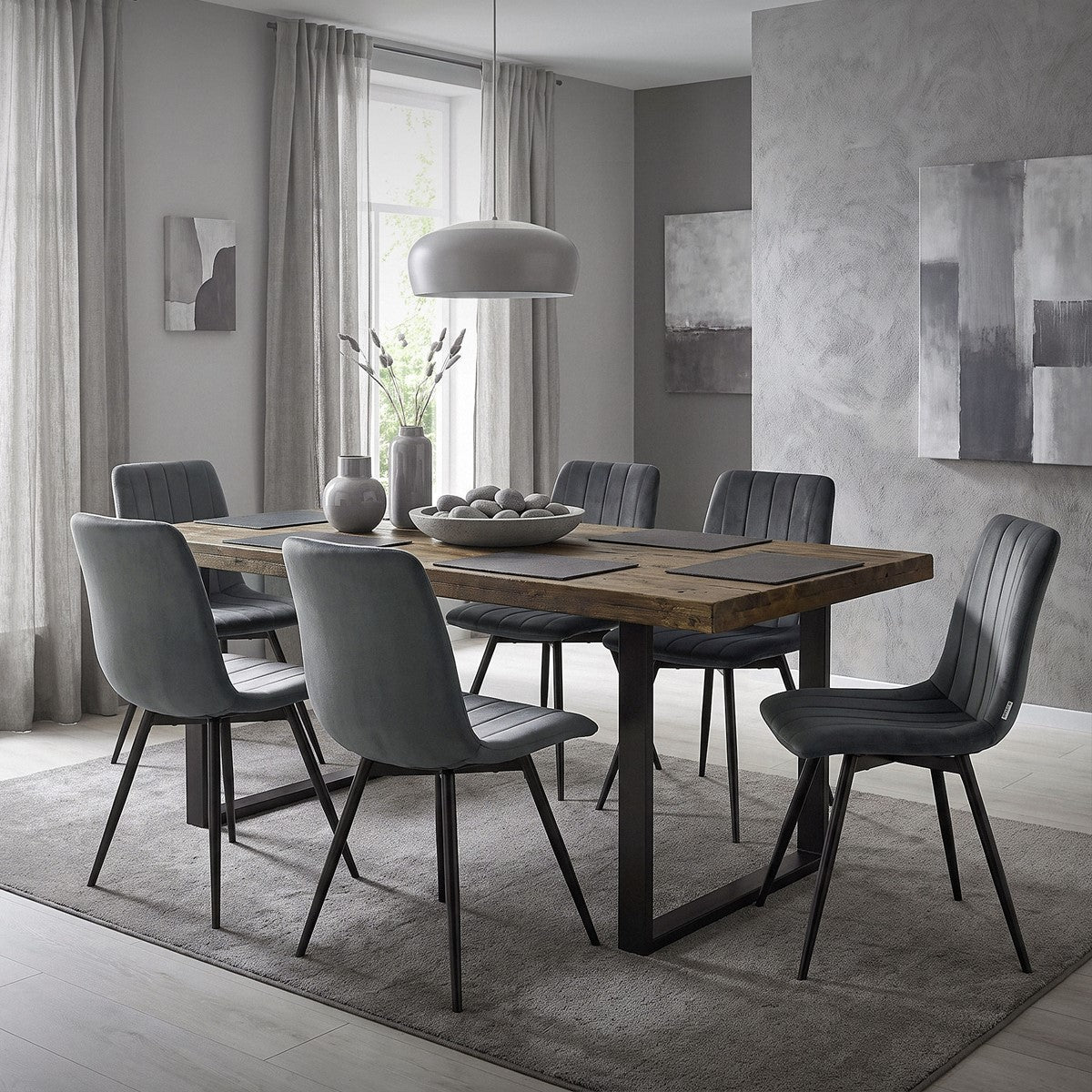 Eetkamer met een houten tafel en zes grijze gestoffeerde stoelen op een vloerkleed.
