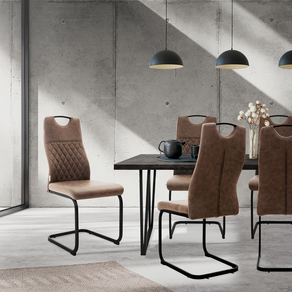Braune Esszimmerstühle mit schwarzen Kufengestellen stehen um einen dunklen Tisch in einem Raum mit Betonwänden.
