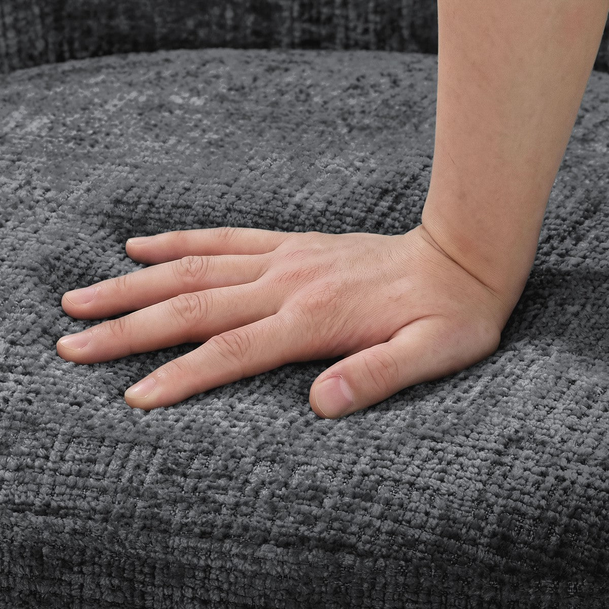 Eine Hand liegt auf der grauen, grob gewebten Polsterfläche eines Stuhls.