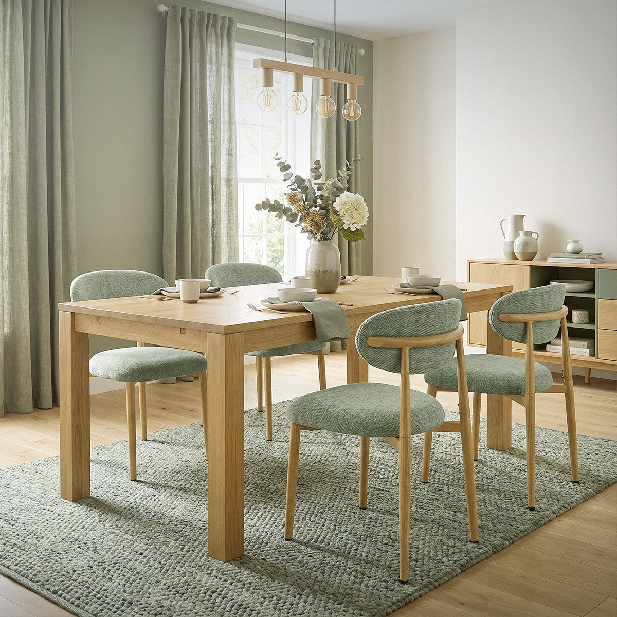 Holztisch mit vier mintgrünen Polsterstühlen auf einem Teppich; Vase mit Blumen, Vorhänge und Sideboard im Esszimmer.