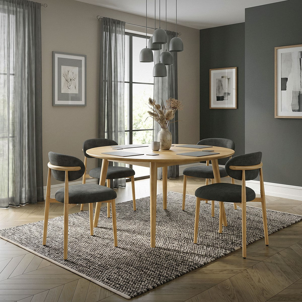 Esszimmer mit rundem Holztisch, vier dunkelgrauen Polsterstühlen, Pendelleuchten und einem Teppich.