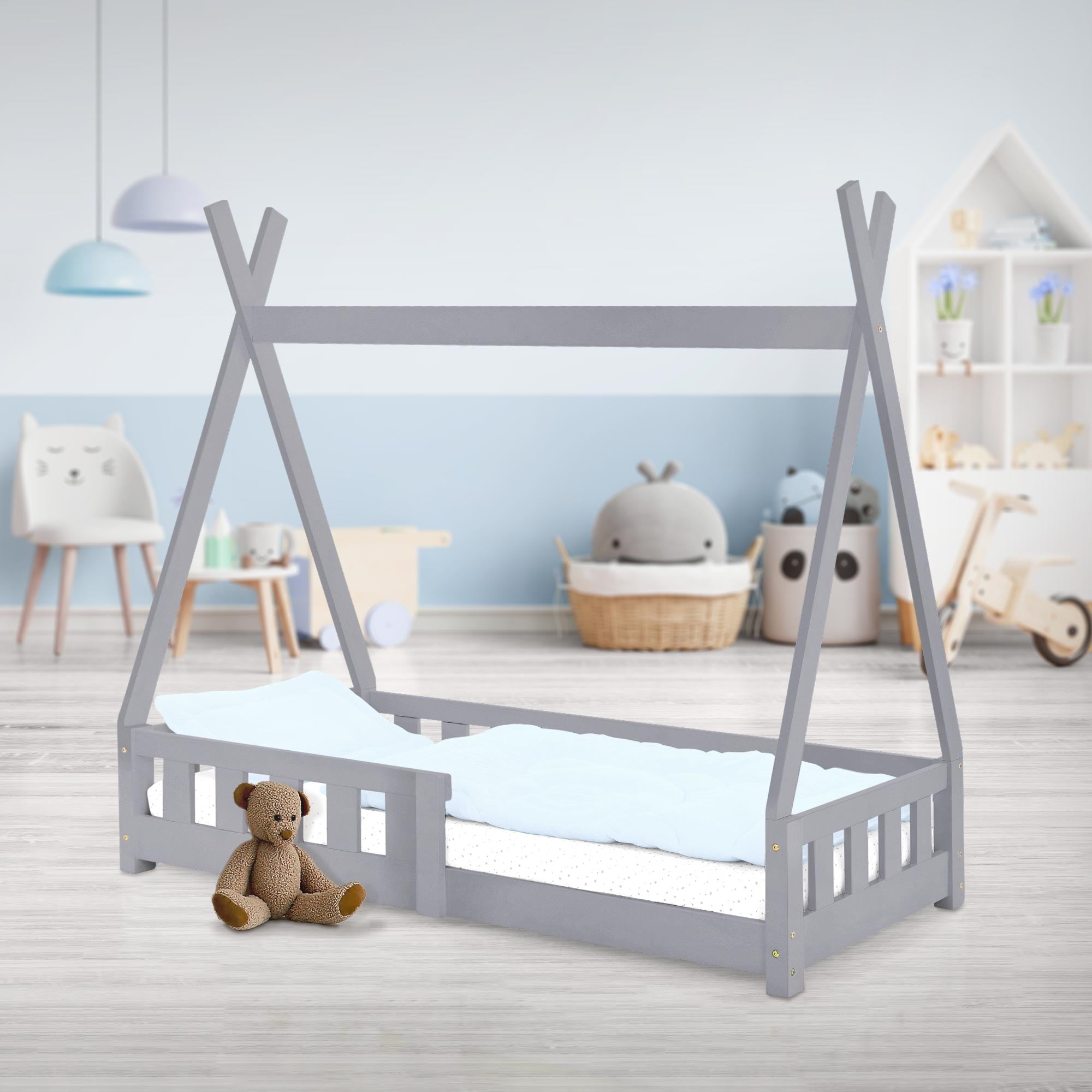 Un lit d'enfant gris en forme de tente avec un ours en peluche et des coussins.
