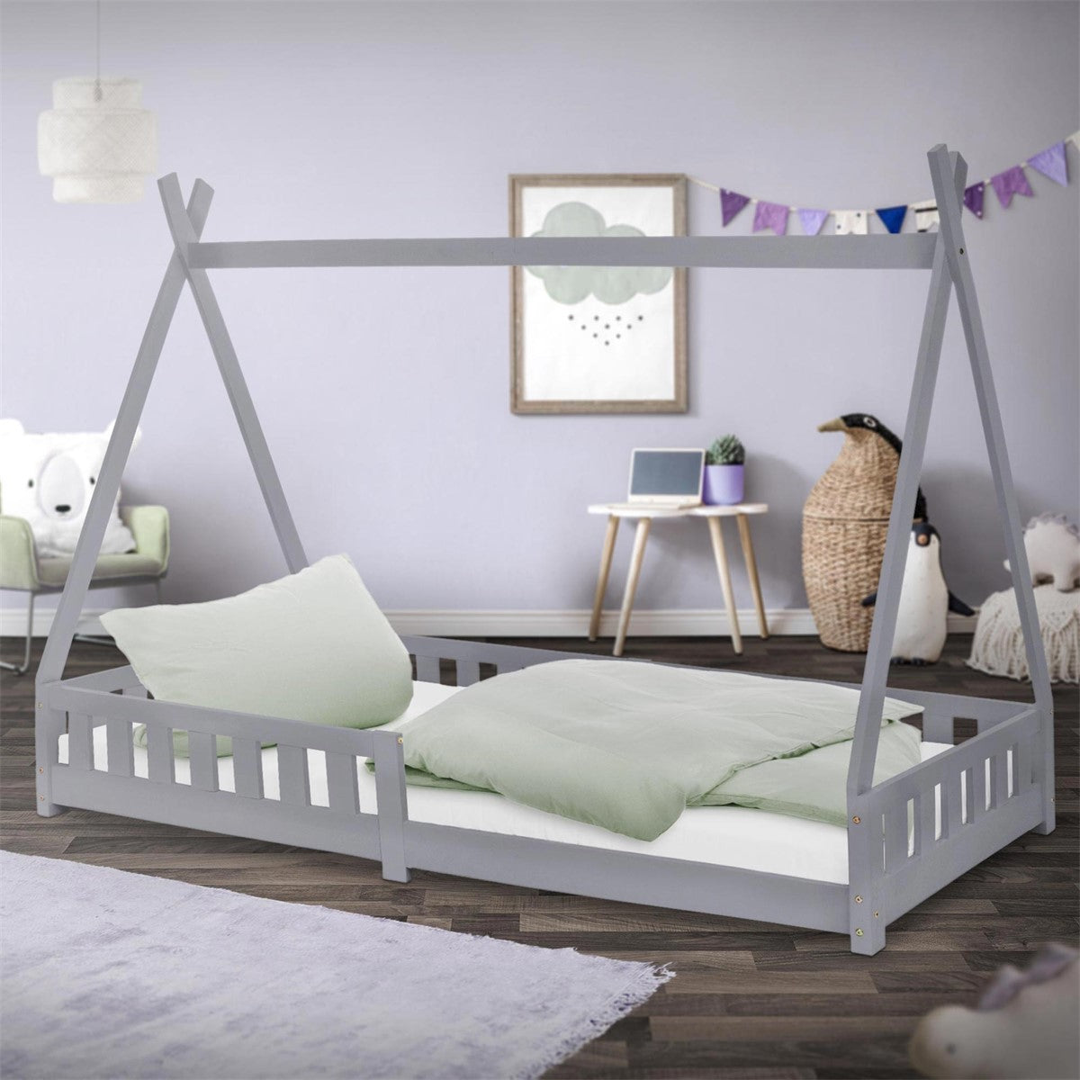 Grijs kinderbed met kussen en deken in de kamer.