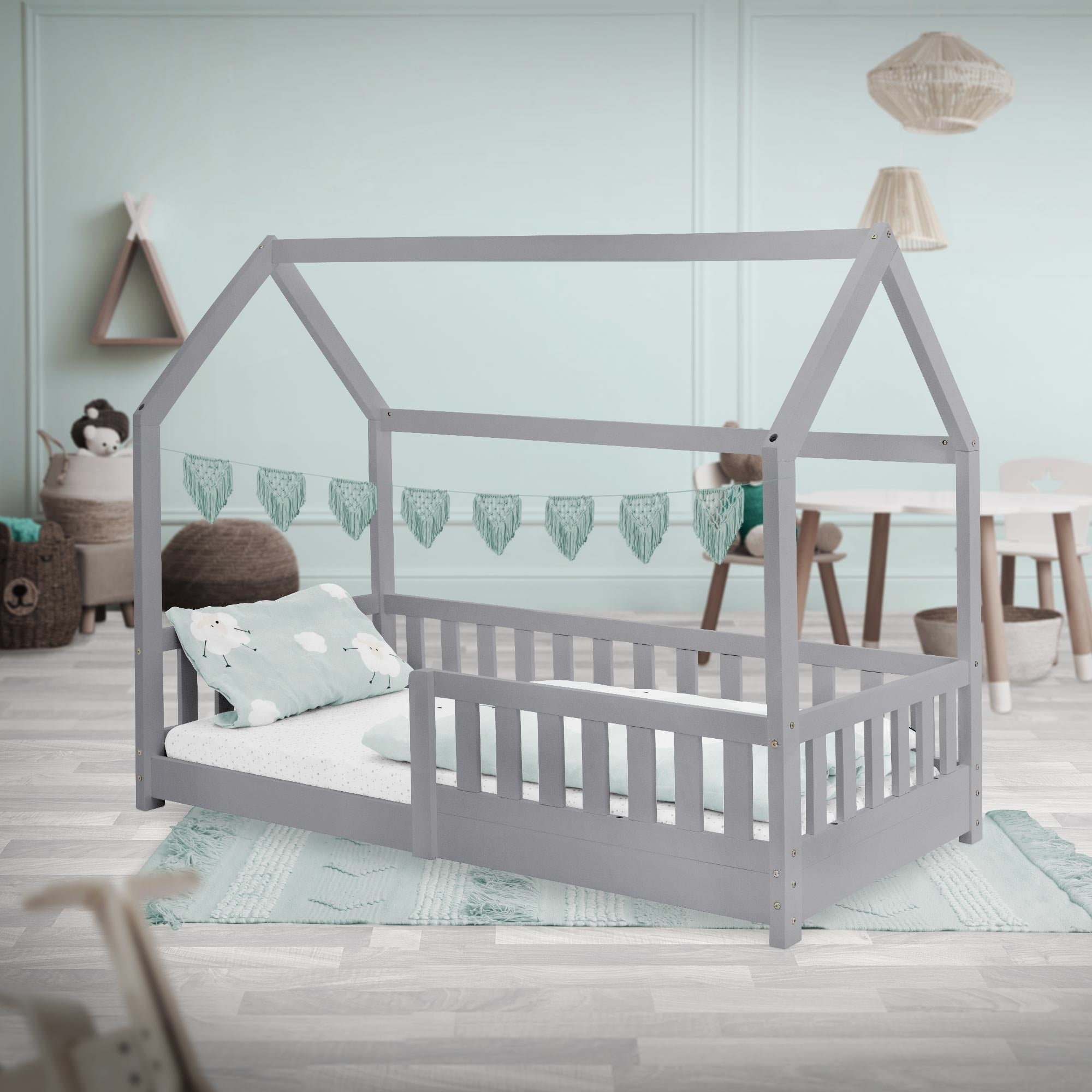 Grau gestrichenes Bett im Kinderzimmer, mit Kissen und Dekoration.