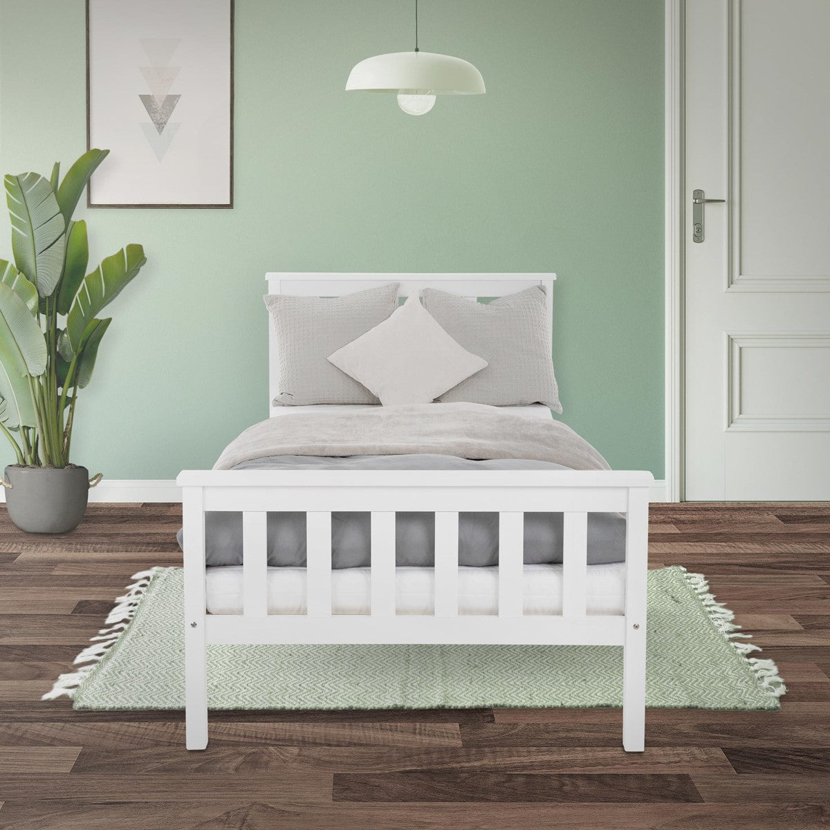 Letto per bambini bianco con sponde alte davanti a una parete verde menta, con biancheria da letto grigia e un cuscino bianco.