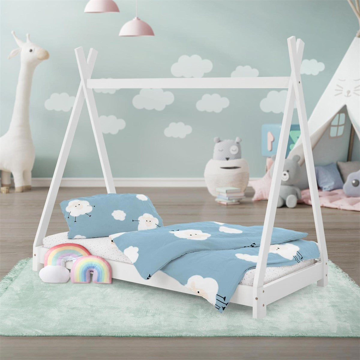 Cama infantil en una habitación con juguetes y un estampado de nubes en la ropa de cama.