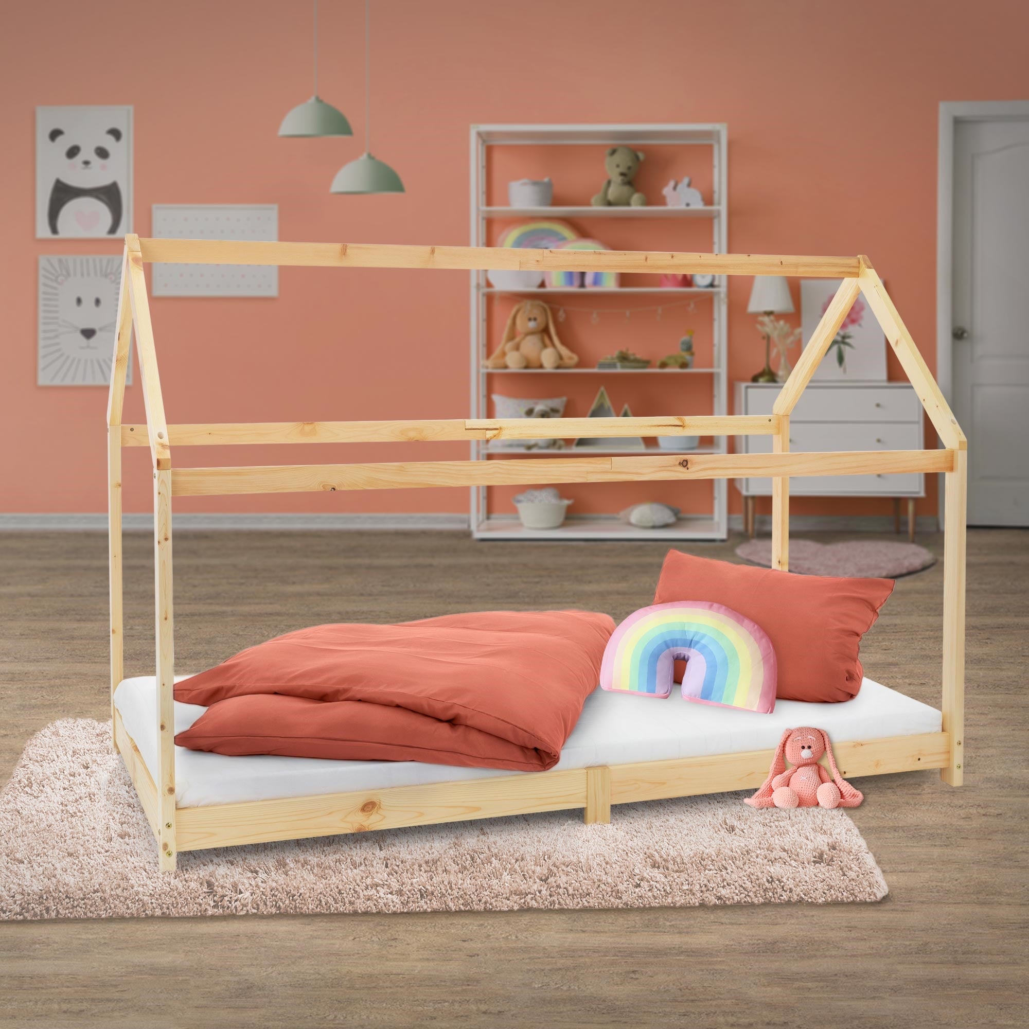 Ein Holzbett im Kinderzimmer mit bunten Kissen und einem Regenbogenkissen.