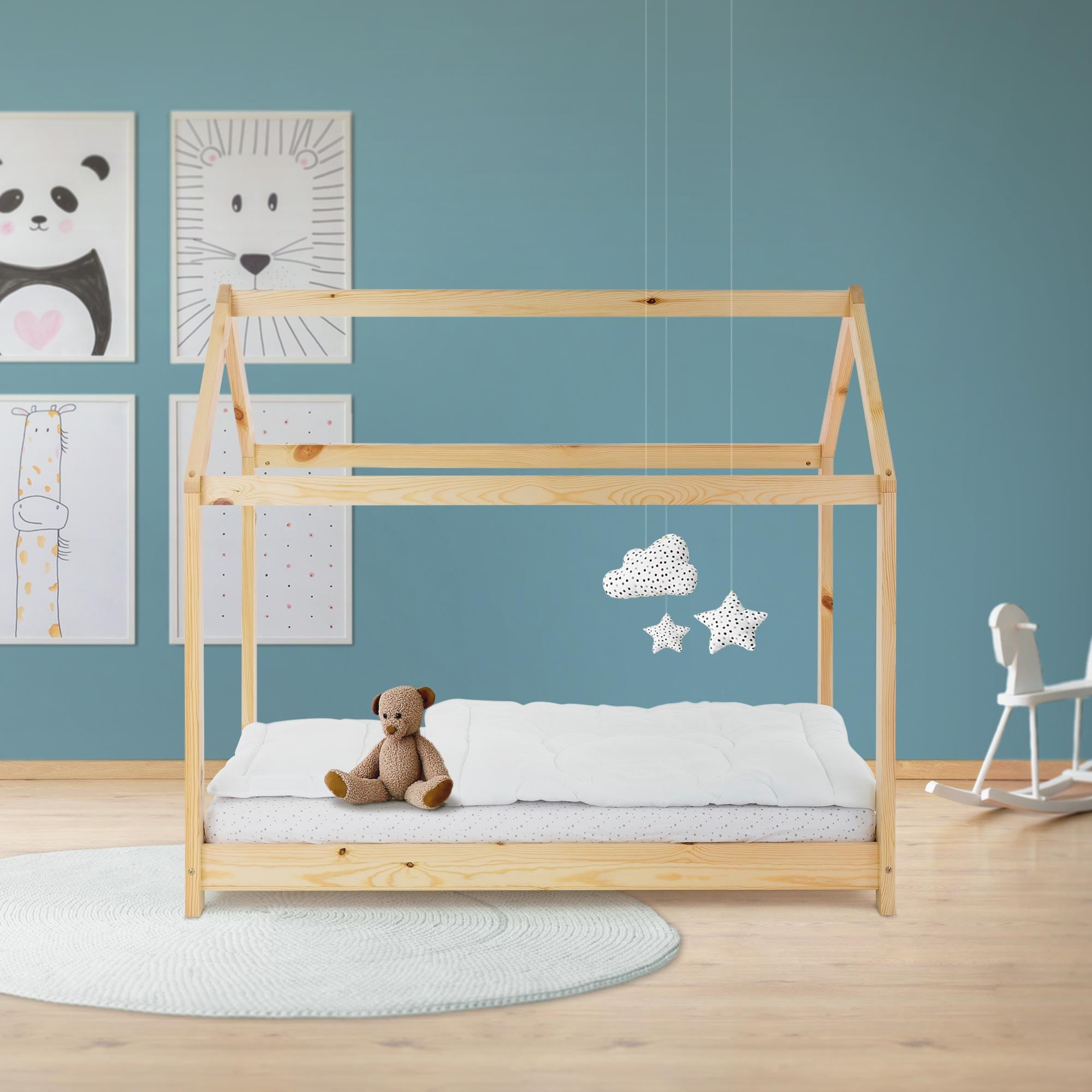 Holz-Kinderbett mit Matratze, Spielzeugbär und bunten Wandbildern.