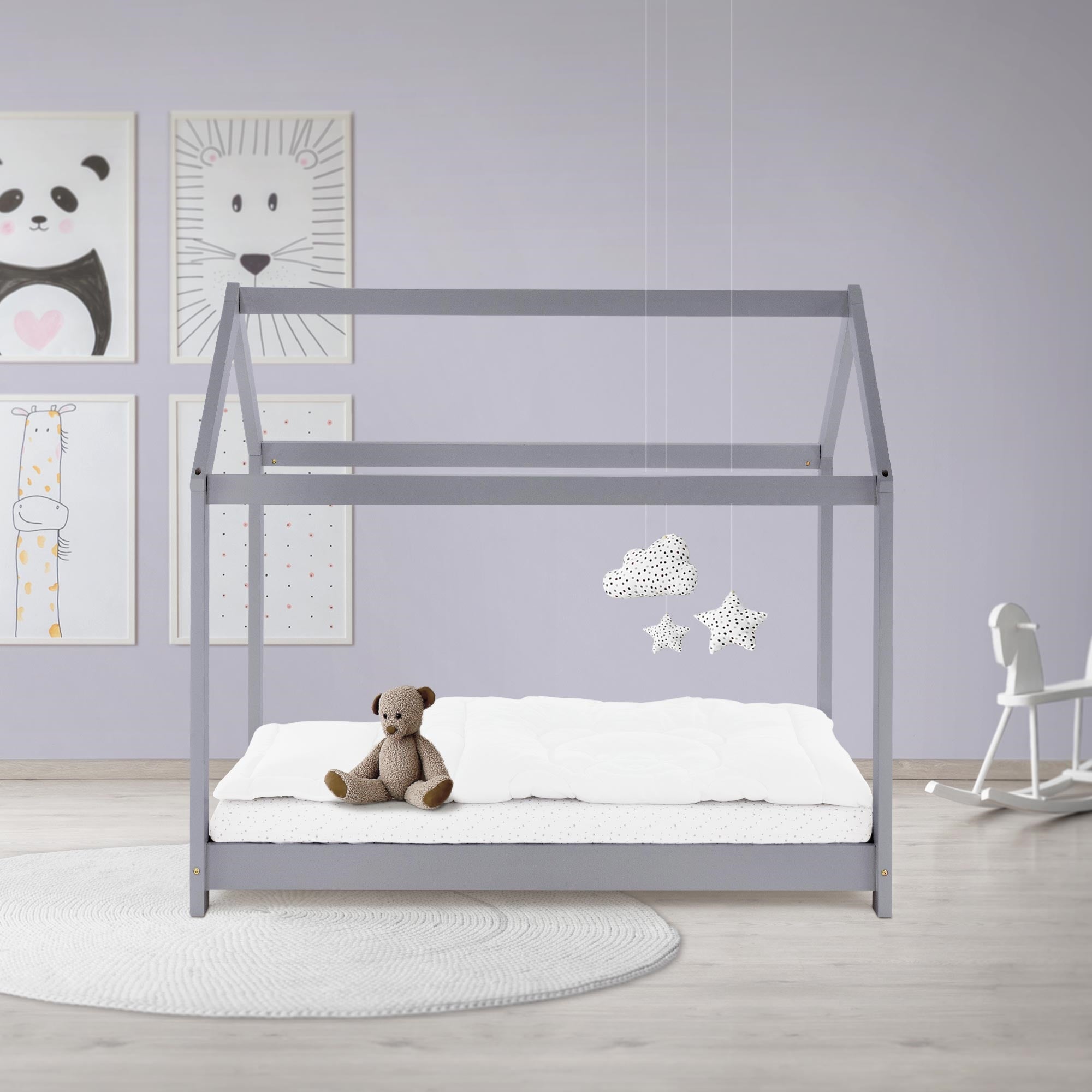 Ein Kinderbett im skandinavischen Stil mit einem Teddy und Wolkenanhängern.