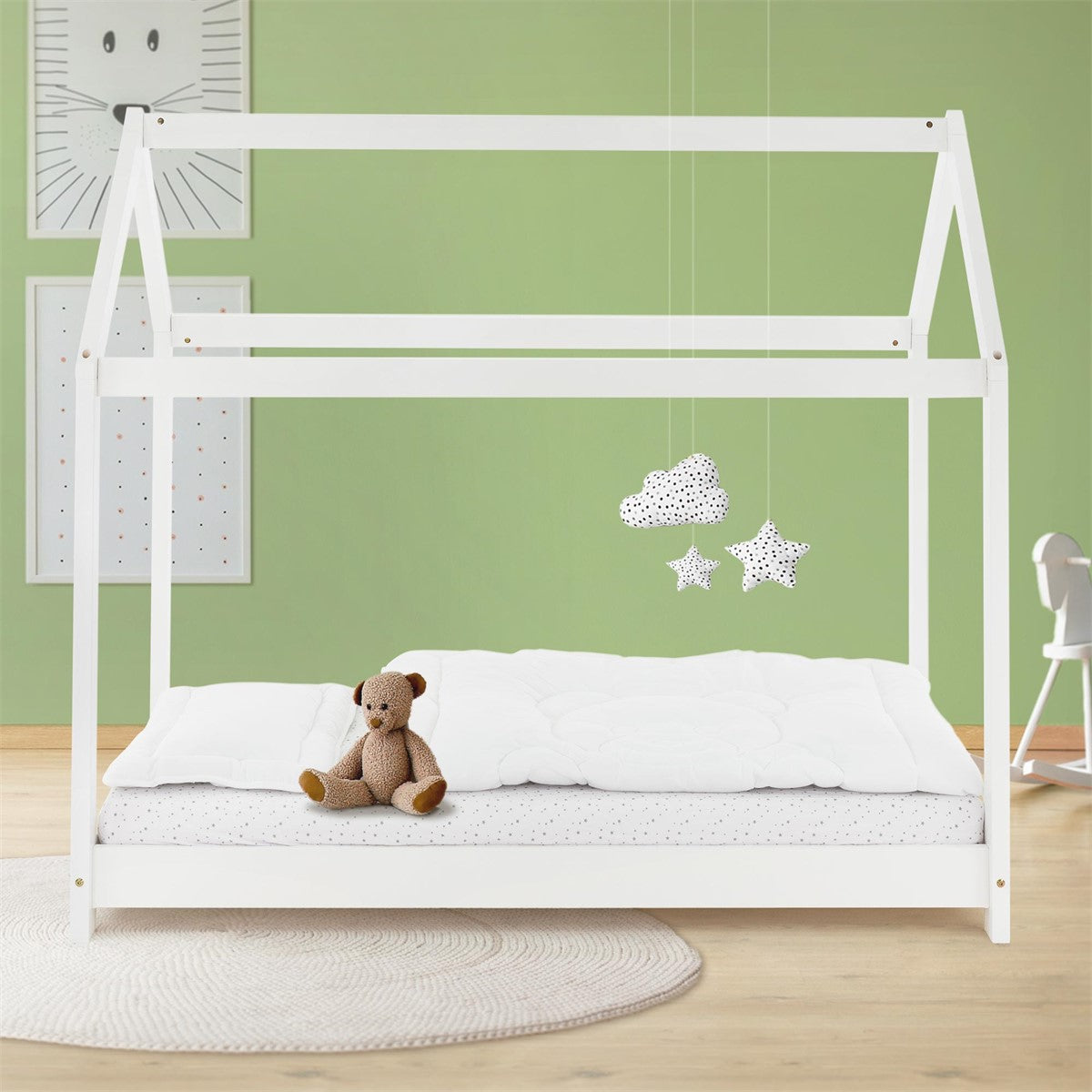 House-shaped bed frame with a teddy bear on the mattress in the room.