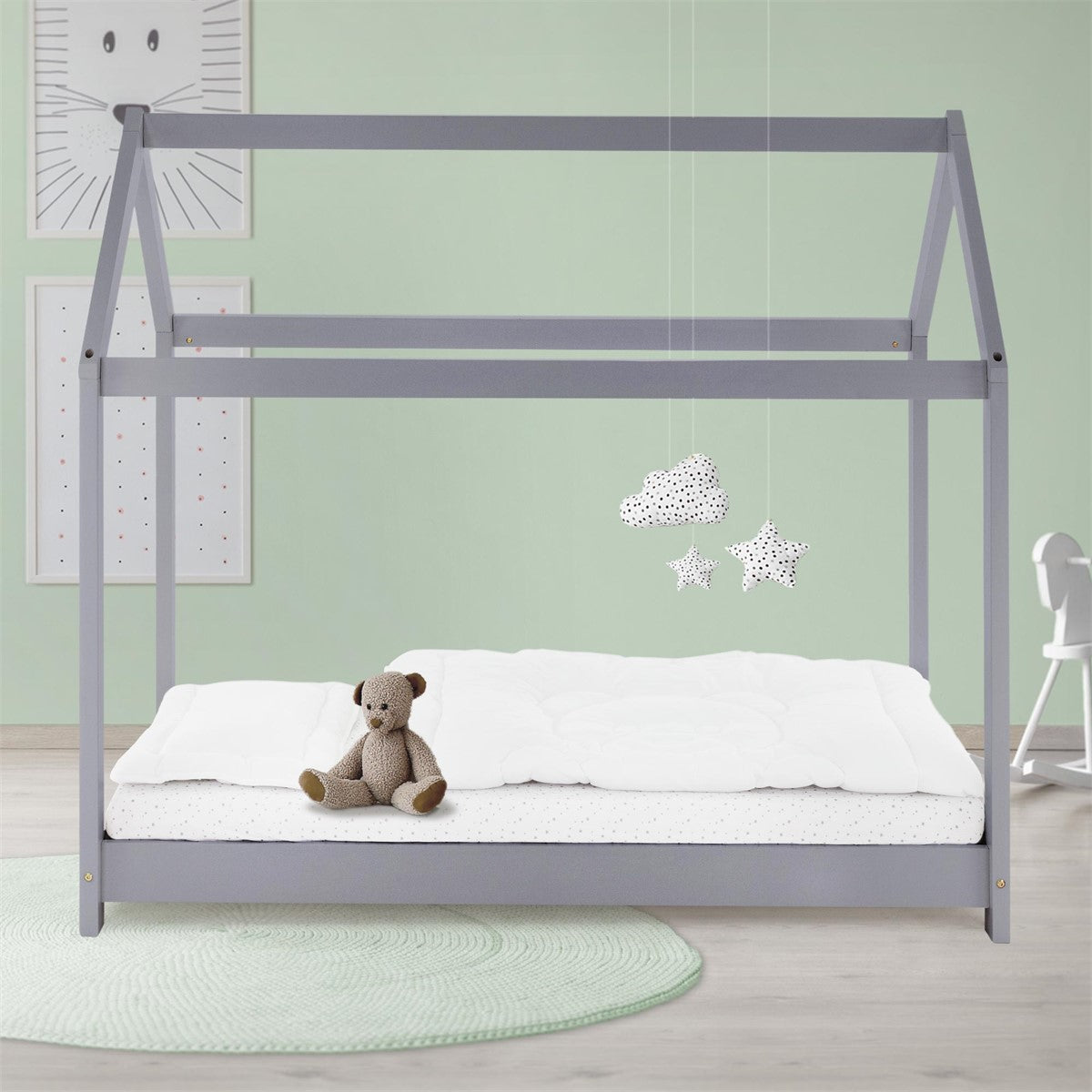 Grey-painted bed frame with a mattress and a stuffed toy on the bed.