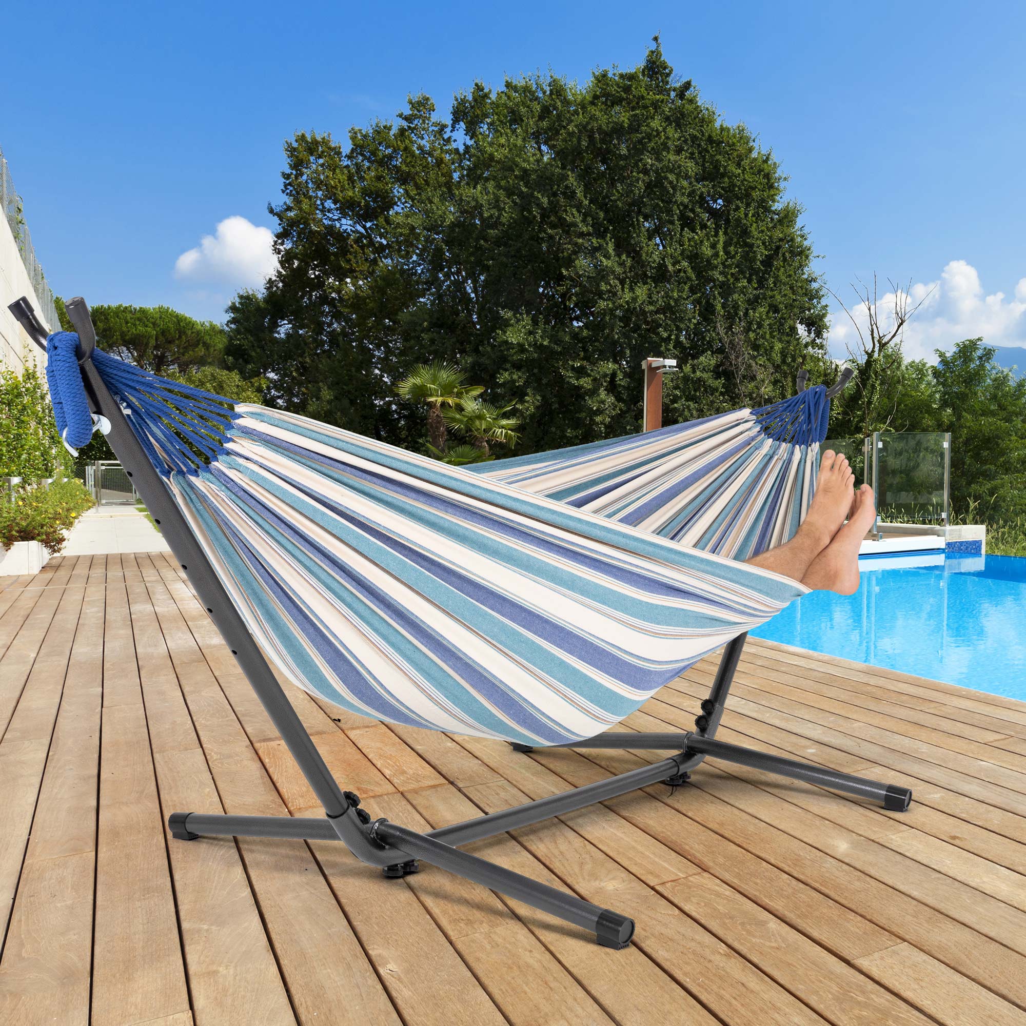 Hängematte mit blauen und weißen Streifen auf Holzterrasse neben einem Pool.